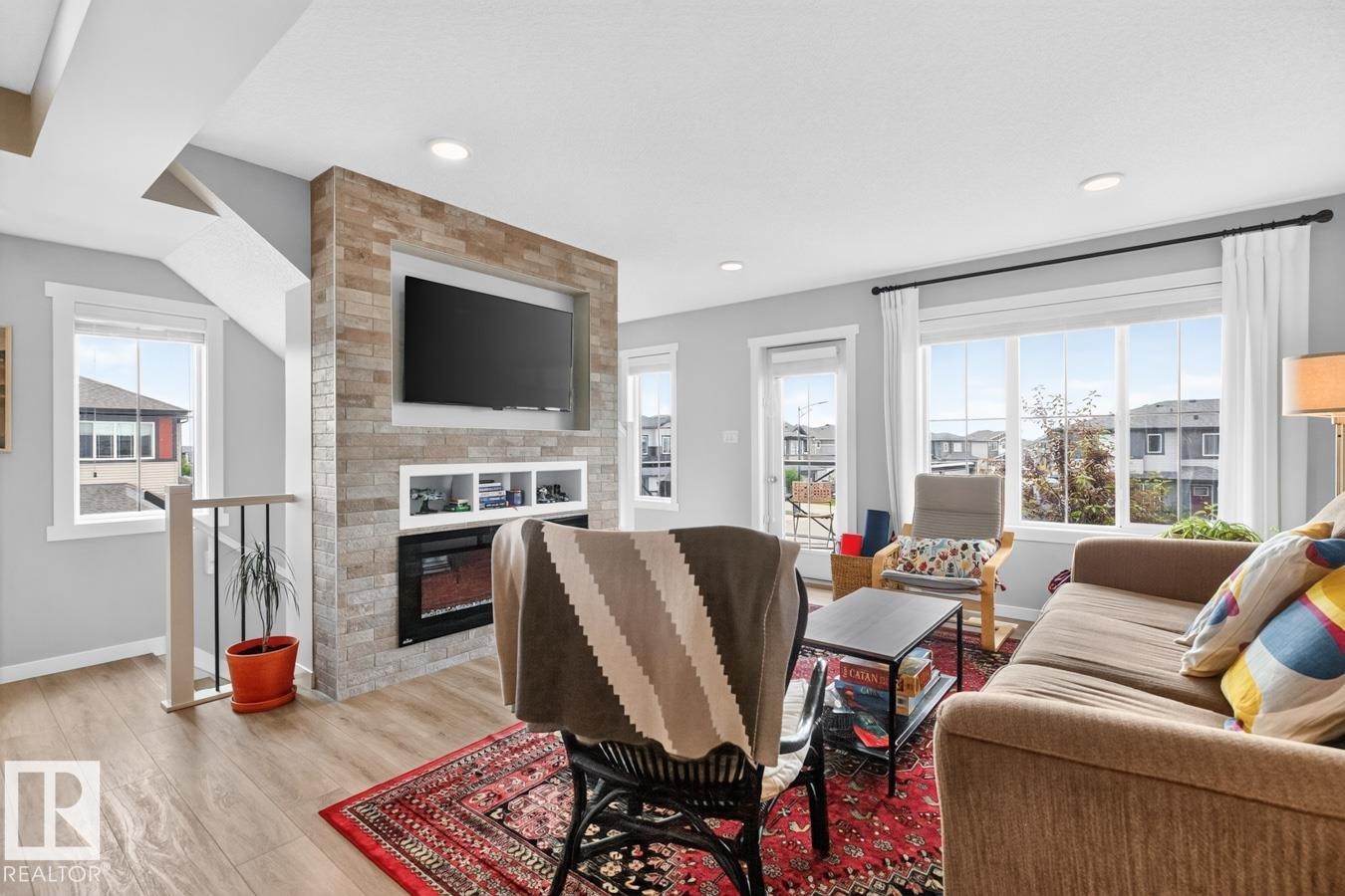 Open Concept Living Room Space featuring Large South Facing Window, Access to Balcony, Electric Fireplace, and Ample Space for Gatherings. - 1051 Cy Becker Road Nw, Edmonton, AB - Indoor Photo Showing Living Room
