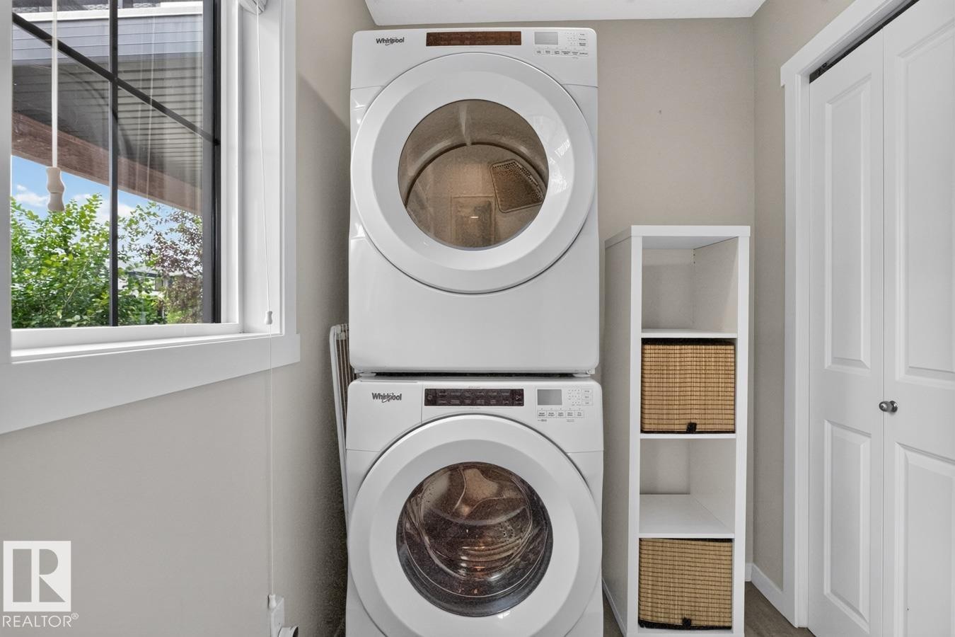 Main Floor Laundry Room featuring Stacking Washer and Dryer with Storage Space. - 1051 Cy Becker Road Nw, Edmonton, AB - Indoor Photo Showing Laundry Room