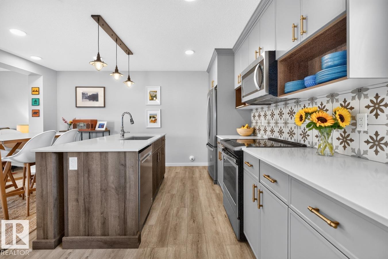 Open Concept Kitchen featuring Stainless Steel Appliances, Stylish Lighting and Accent Tiles, Bar Fridge, and Bar/Counter Seating. - 1051 Cy Becker Road Nw, Edmonton, AB - Indoor Photo Showing Kitchen With Upgraded Kitchen