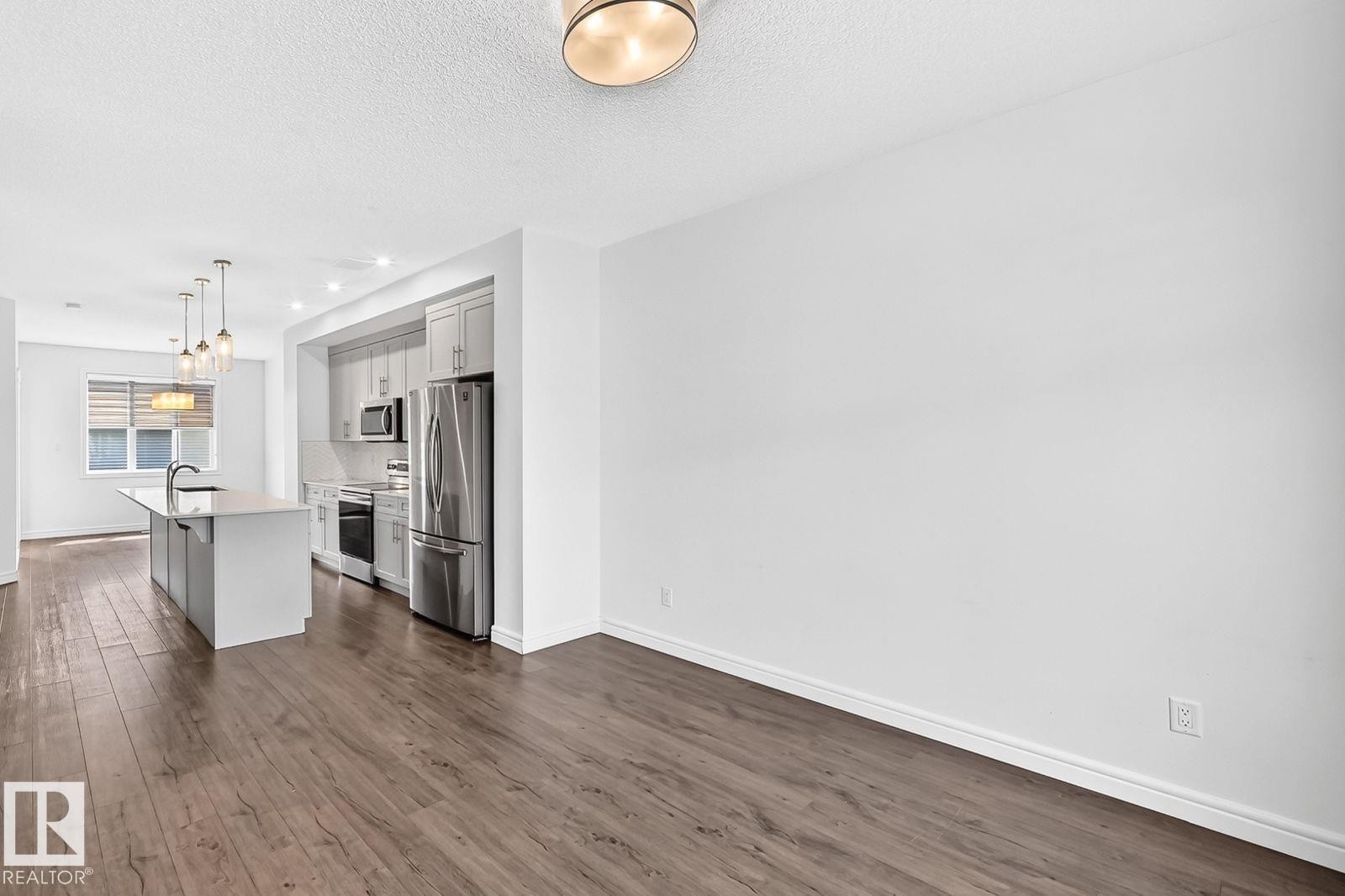 Open-concept kitchen featuring an island with an undermount sink, stainless steel appliances, light-toned cabinetry, and recessed lighting - 1261 Rosenthal Boulevard Nw, Edmonton, AB - Indoor Photo Showing Kitchen