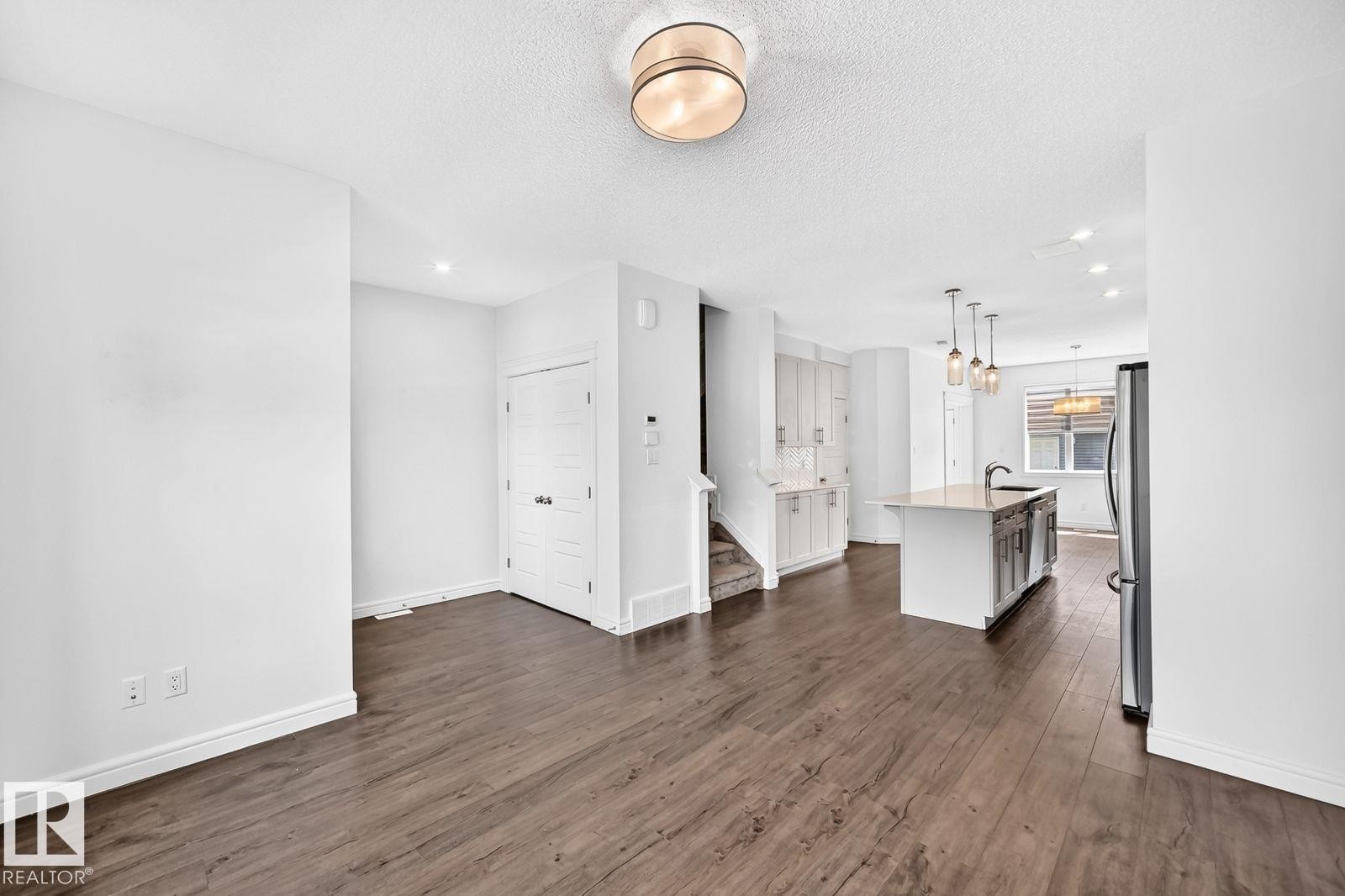 Open-concept living space featuring wood-finish flooring, recessed lighting, and a contemporary ceiling fixture - 1261 Rosenthal Boulevard Nw, Edmonton, AB - Indoor