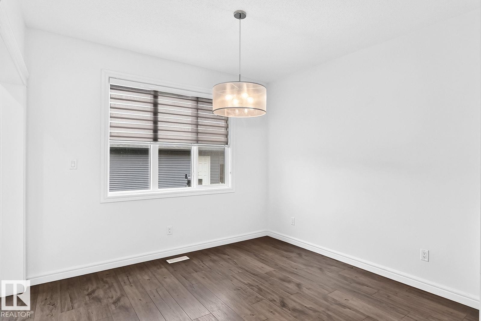 Bright room featuring a contemporary window with blinds, wood-finish flooring, a drum pendant light fixture, white walls, and white trim - 1261 Rosenthal Boulevard Nw, Edmonton, AB - Indoor Photo Showing Other Room