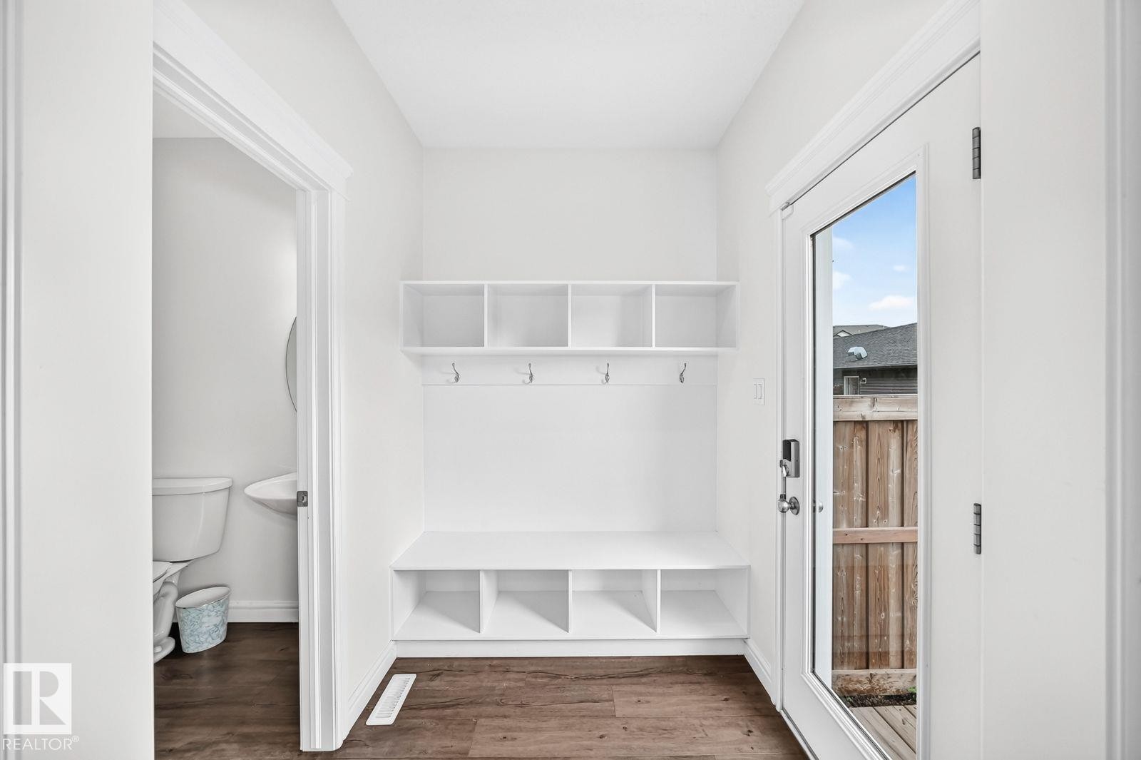 Entryway featuring built-in white cabinetry with open shelving and storage cubbies, integrated bench seating, and wall-mounted hooks - 1261 Rosenthal Boulevard Nw, Edmonton, AB - Indoor Photo Showing Other Room