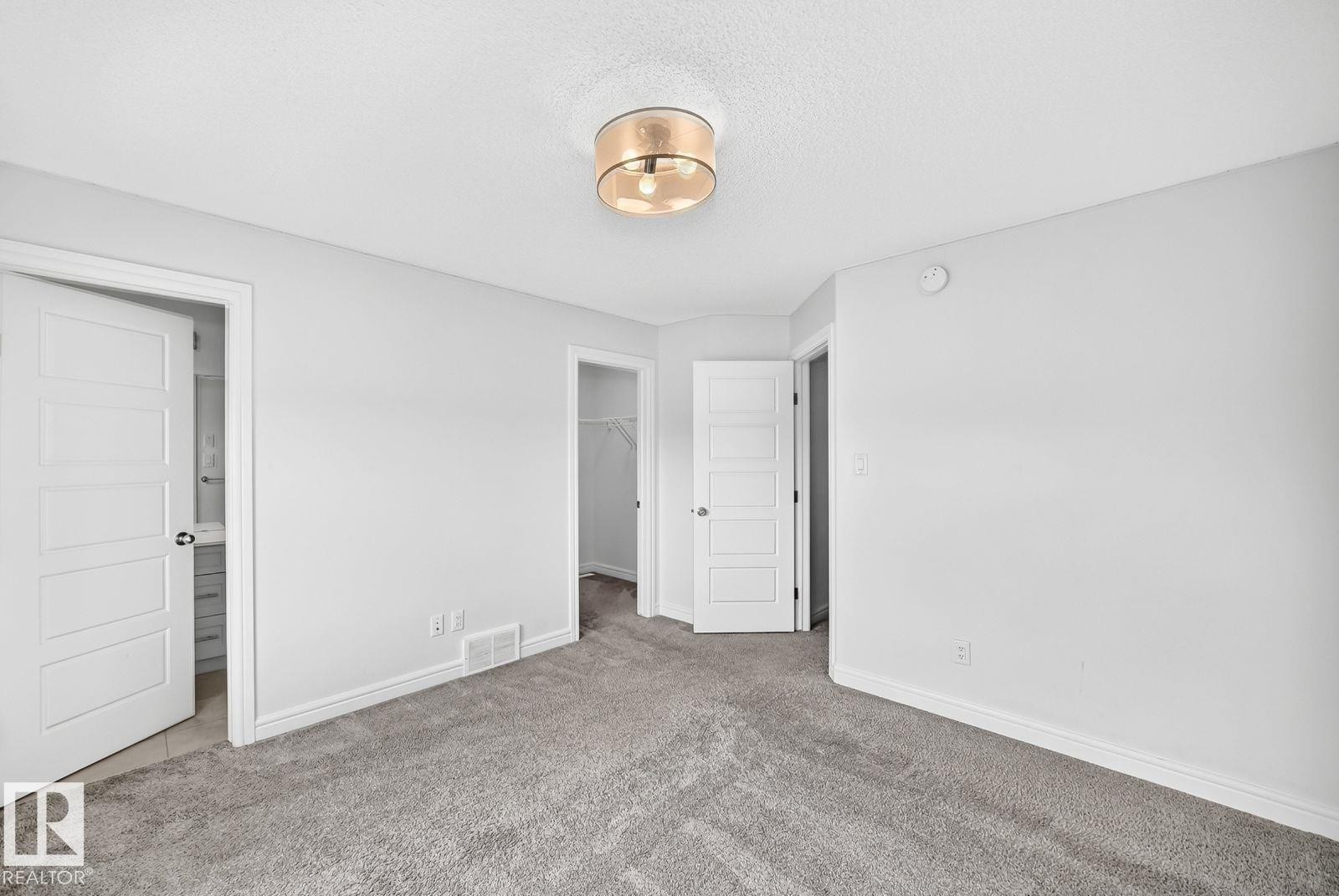 Carpeted room featuring light gray walls and a contemporary ceiling light fixture - 1261 Rosenthal Boulevard Nw, Edmonton, AB - Indoor Photo Showing Other Room