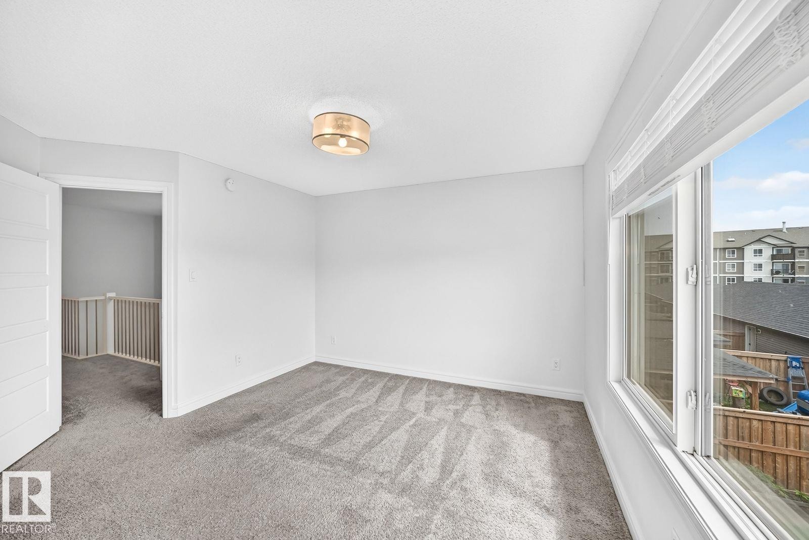Bright room featuring neutral gray carpeting and white painted walls - 1261 Rosenthal Boulevard Nw, Edmonton, AB - Indoor Photo Showing Other Room