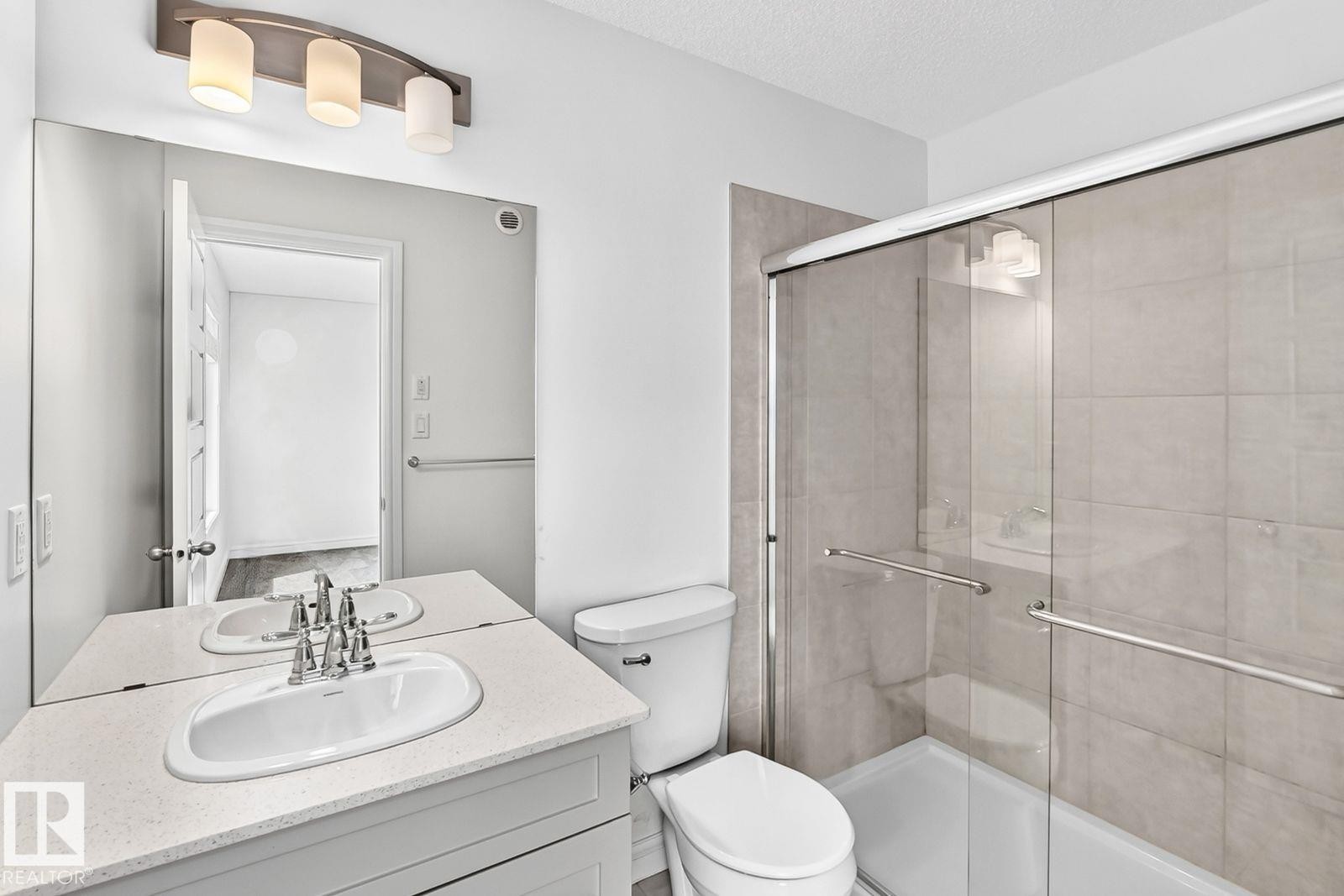 Bathroom featuring a vanity with an integrated sink, a large wall-mounted mirror, and a three-light fixture - 1261 Rosenthal Boulevard Nw, Edmonton, AB - Indoor Photo Showing Bathroom
