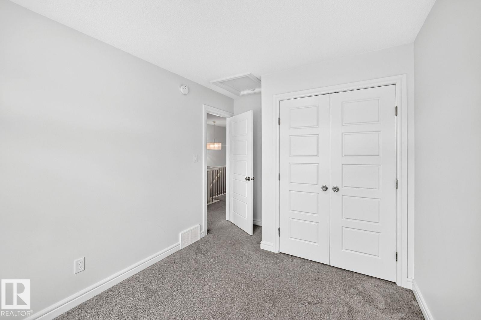 White paneled bi-fold closet doors, light gray wall color, gray carpeting, and white baseboards - 1261 Rosenthal Boulevard Nw, Edmonton, AB - Indoor Photo Showing Other Room