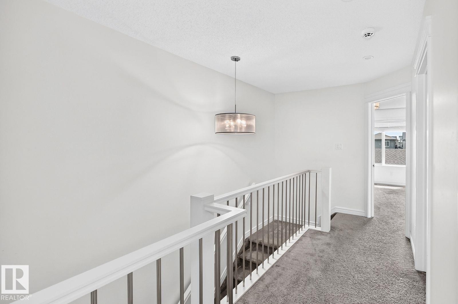 Upper-level hallway with textured ceiling, pendant light fixture, and plush gray carpeting - 1261 Rosenthal Boulevard Nw, Edmonton, AB - Indoor Photo Showing Other Room