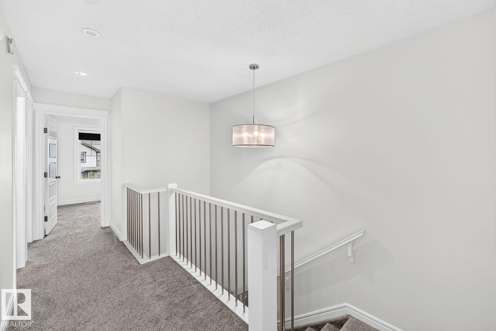 Carpeted hallway and staircase featuring contemporary metal balusters and a white handrail - 1261 Rosenthal Boulevard Nw, Edmonton, AB - Indoor Photo Showing Other Room