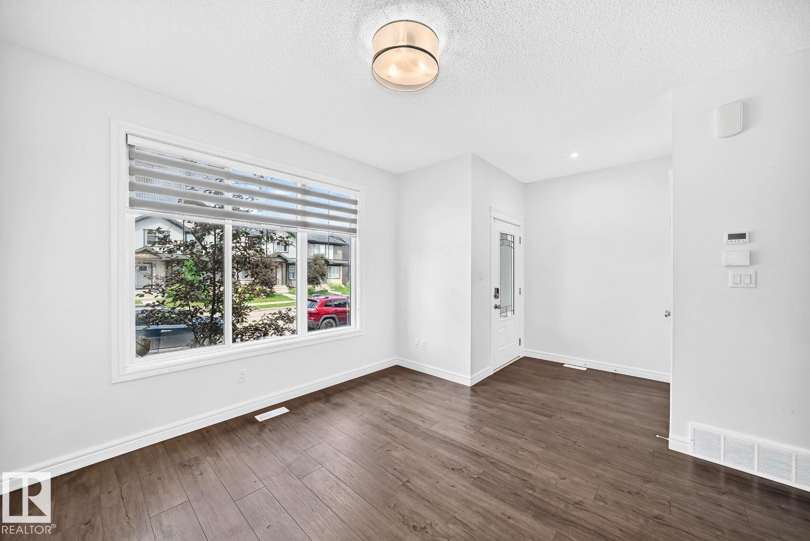 Spacious room featuring wood-finish flooring, a large multi-pane window with blinds, and recessed lighting - 1261 Rosenthal Boulevard Nw, Edmonton, AB - Indoor