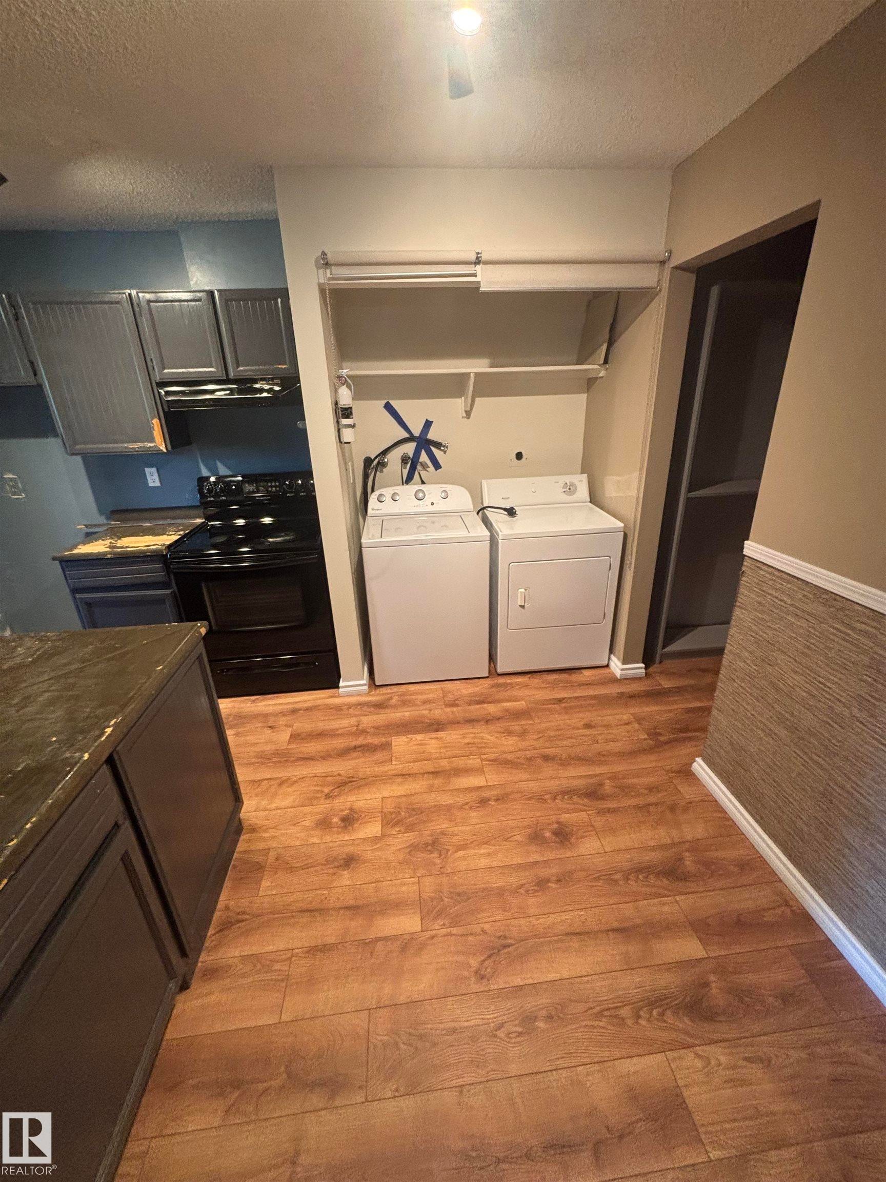 Dedicated laundry area featuring a washer and dryer, adjacent to an open shelving system - #206 2311 119 St Nw, Edmonton, AB - Indoor Photo Showing Laundry Room