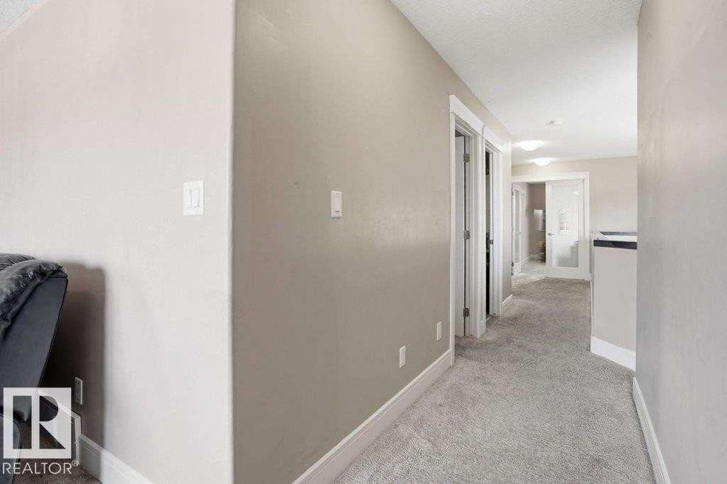 Carpeted hallway featuring warm neutral wall tones and white baseboards - 258 Albany Drive Nw, Edmonton, AB - Indoor Photo Showing Other Room