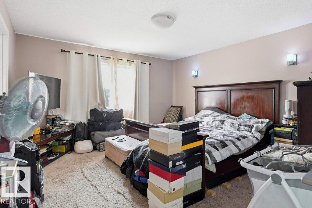 Spacious bedroom featuring light-colored walls, a ceiling-mounted light fixture, and two wall sconces providing ambient lighting - 258 Albany Drive Nw, Edmonton, AB - Indoor Photo Showing Bedroom