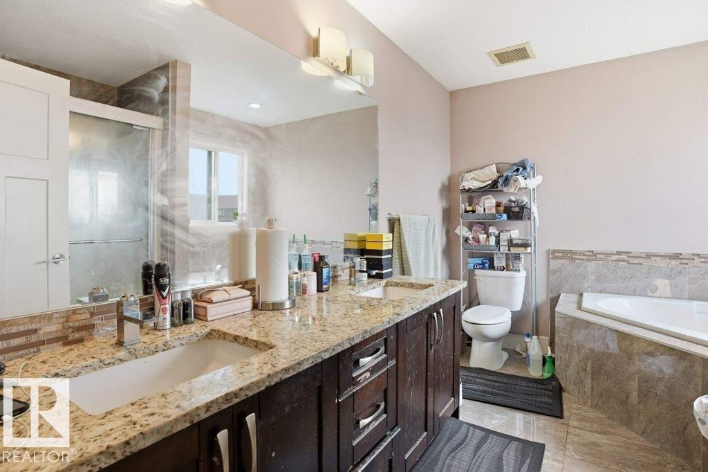 Dual basin vanity with granite countertops, rich wood-finish cabinetry, and a tile backsplash - 258 Albany Drive Nw, Edmonton, AB - Indoor Photo Showing Bathroom
