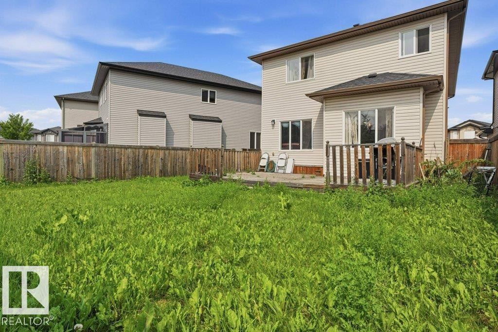 Expansive fenced backyard featuring a wooden deck, sliding glass door access, and vinyl siding - 258 Albany Drive Nw, Edmonton, AB - Outdoor