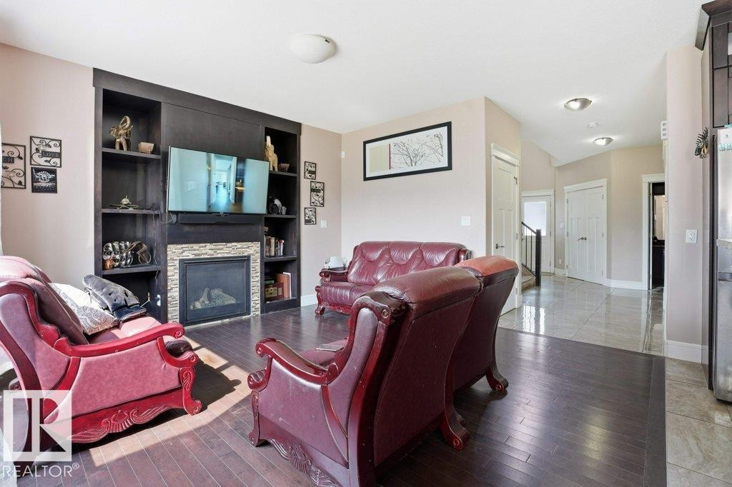 Living area with a built-in media center featuring dark wood shelving and a stone-clad fireplace - 258 Albany Drive Nw, Edmonton, AB - Indoor Photo Showing Living Room With Fireplace