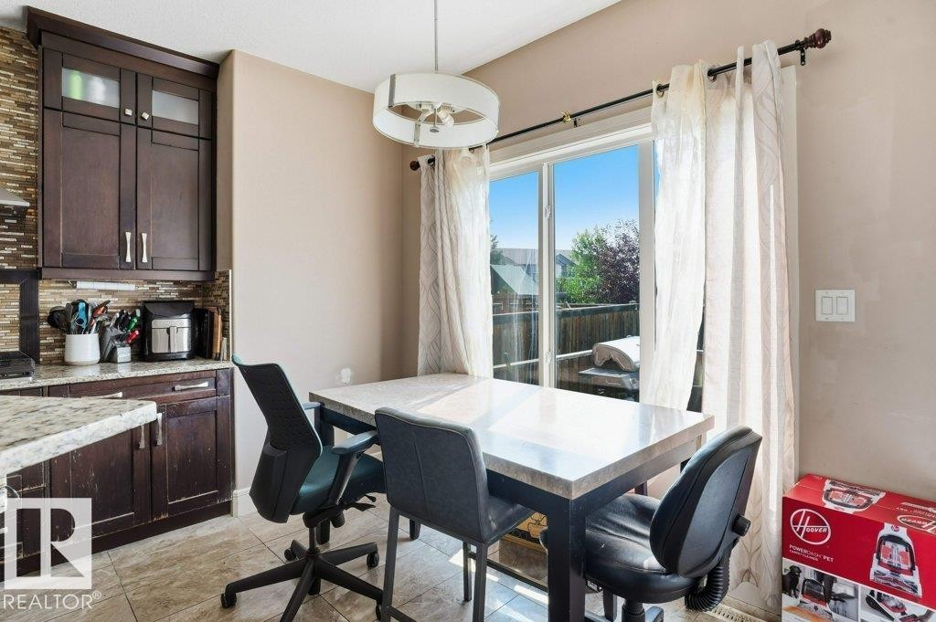 Kitchen dining area featuring a sliding glass door, dark wood cabinetry, a tile backsplash, and a light fixture - 258 Albany Drive Nw, Edmonton, AB - Indoor Photo Showing Other Room