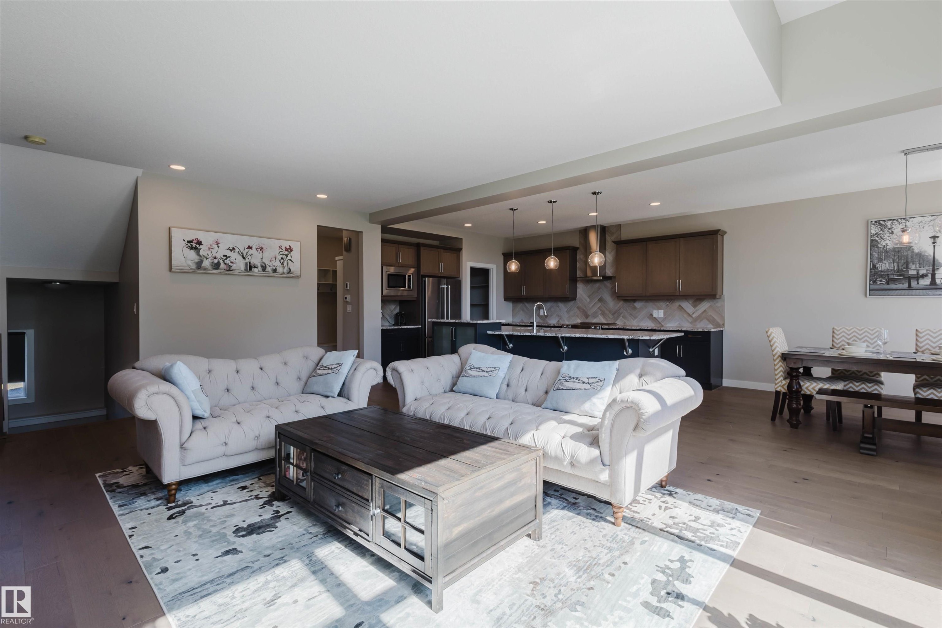 Open-concept living space featuring wood-finish flooring, recessed lighting, and a neutral color palette - 4125 Kennedy Green Sw, Edmonton, AB - Indoor Photo Showing Living Room