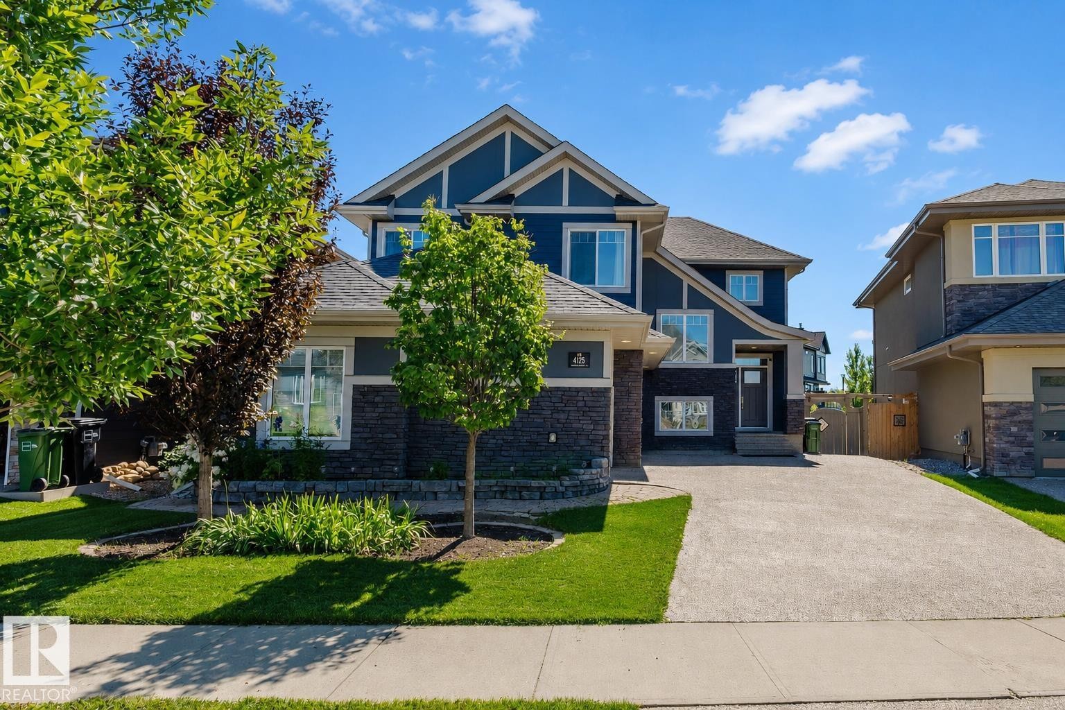 Contemporary two-story residence featuring a dark blue exterior with stone accents and white trim - 4125 Kennedy Green Sw, Edmonton, AB - Outdoor With Facade