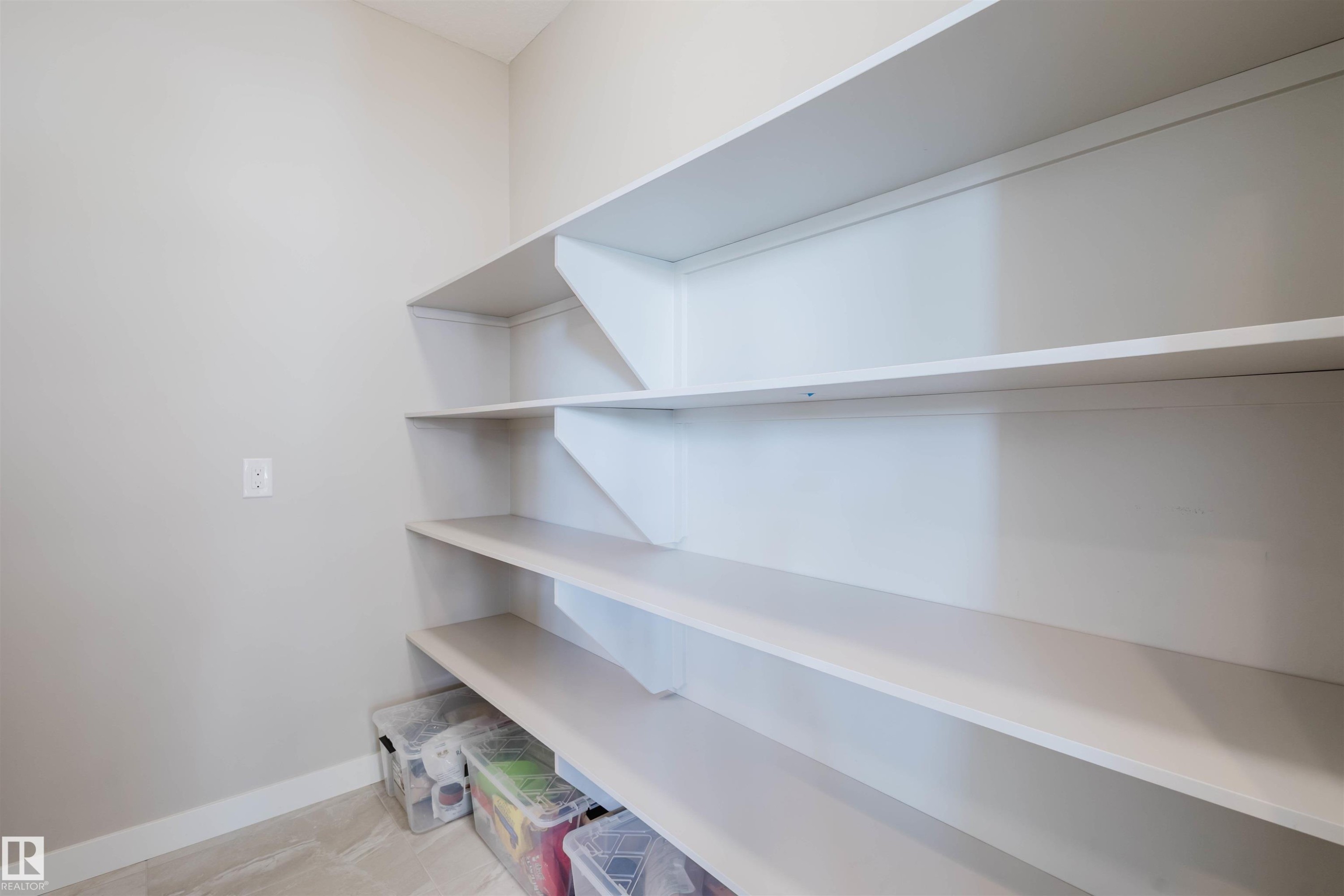 Built-in shelving unit with multiple levels, light-toned walls, and neutral flooring - 4125 Kennedy Green Sw, Edmonton, AB - Indoor With Storage