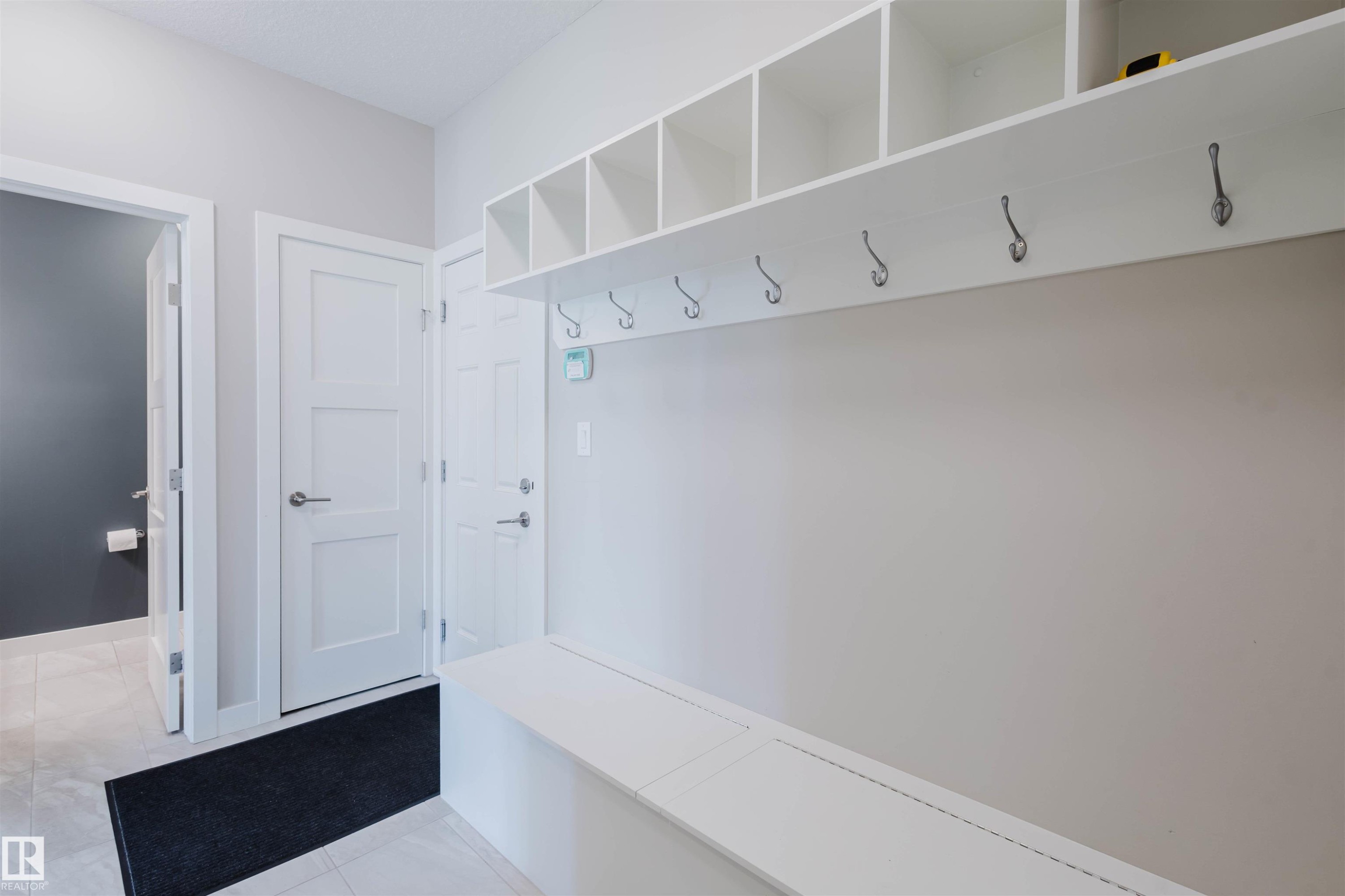 Entryway featuring a built-in white bench, overhead cubby storage, and coat hooks - 4125 Kennedy Green Sw, Edmonton, AB - Indoor Photo Showing Other Room