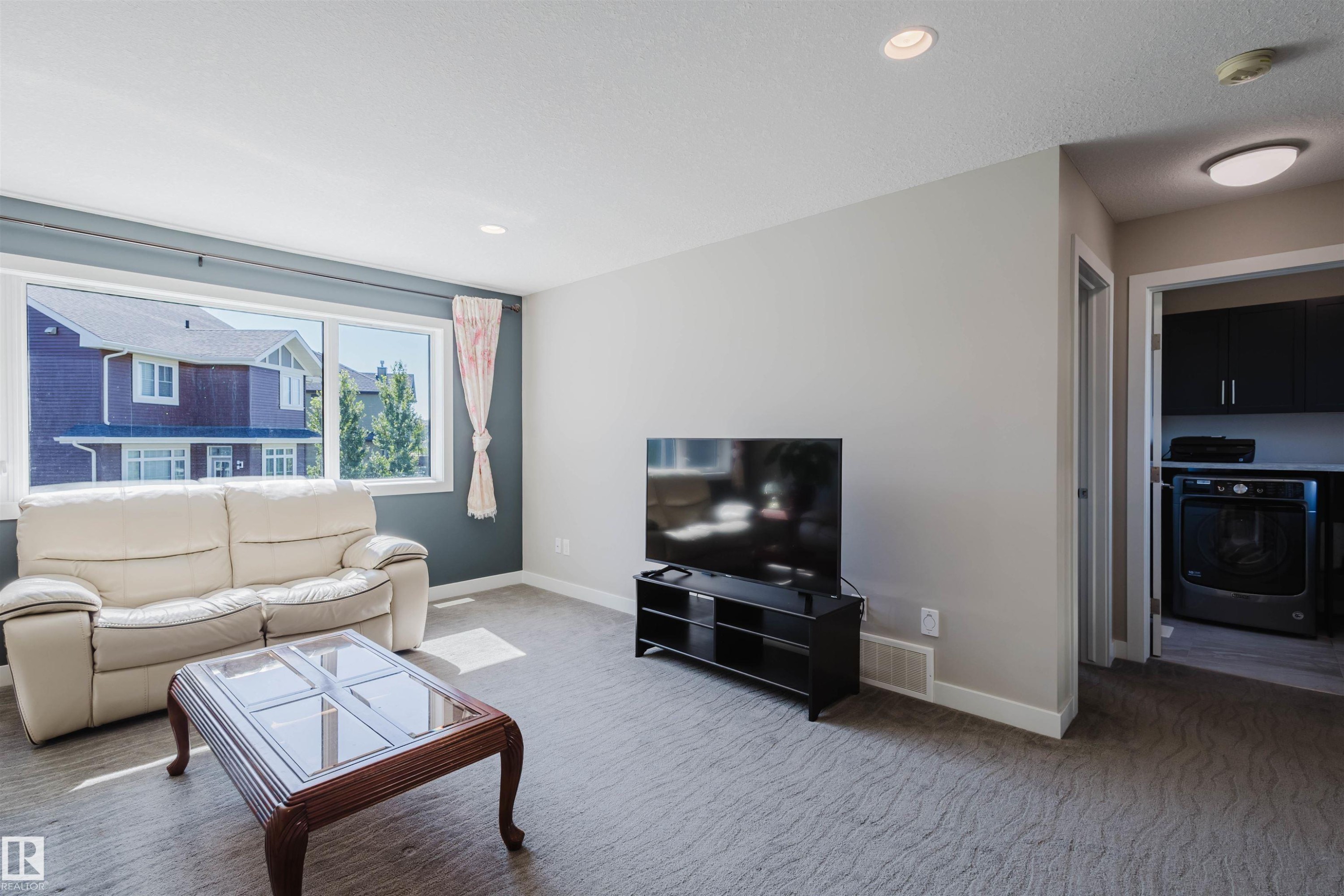 Living area with a wide window, recessed lighting, and patterned carpeting - 4125 Kennedy Green Sw, Edmonton, AB - Indoor Photo Showing Living Room