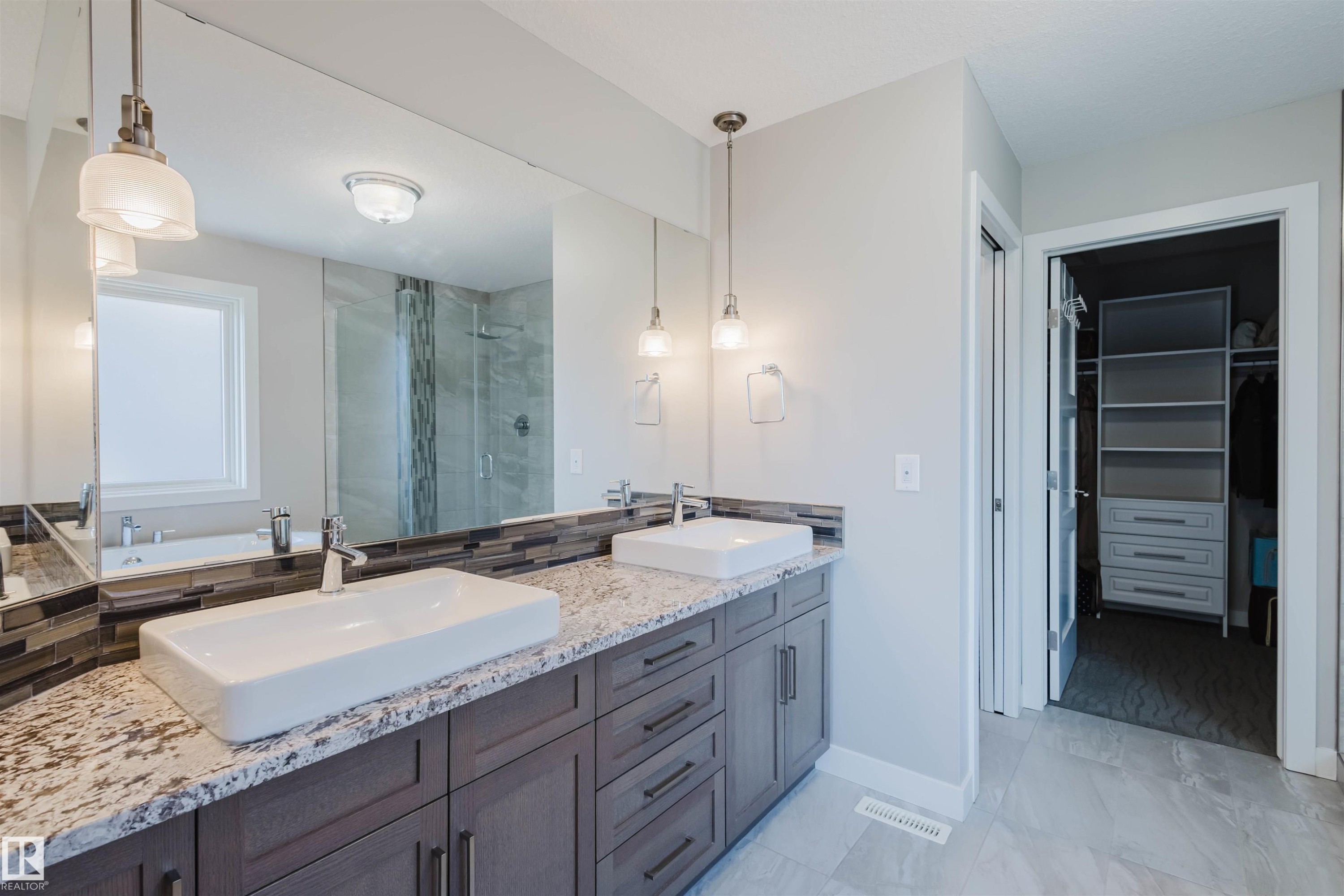 Dual vessel sinks set on a granite-finish countertop with dark wood cabinetry - 4125 Kennedy Green Sw, Edmonton, AB - Indoor Photo Showing Bathroom