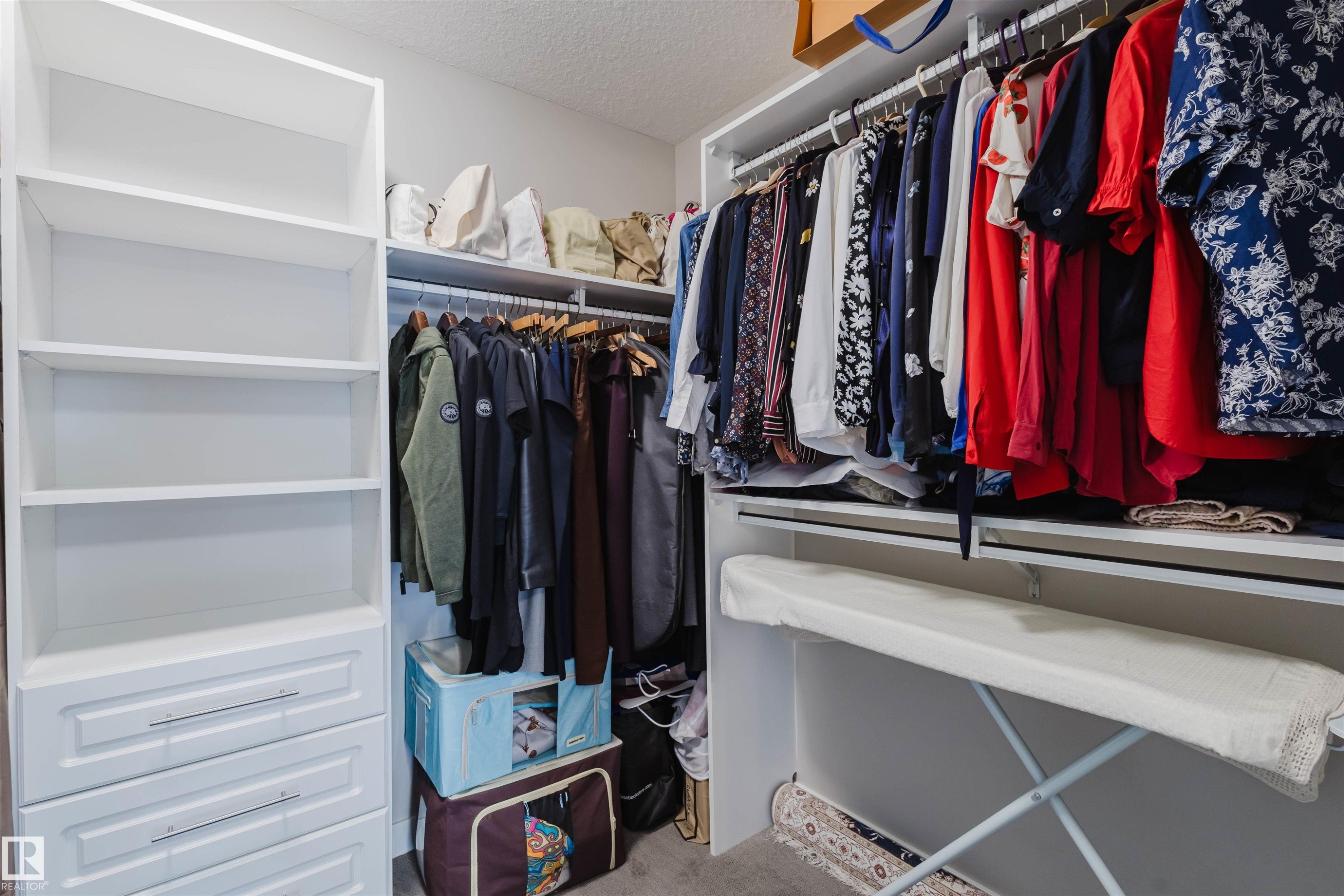 Custom white built-in closet system featuring open shelving, multiple hanging rods, and integrated drawers with horizontal pulls - 4125 Kennedy Green Sw, Edmonton, AB - Indoor With Storage