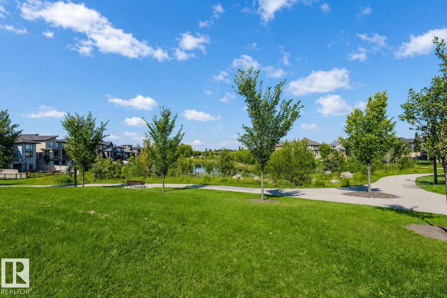 Expansive green space featuring a paved walking path, mature trees, and a distant water feature - 4125 Kennedy Green Sw, Edmonton, AB - Outdoor With View