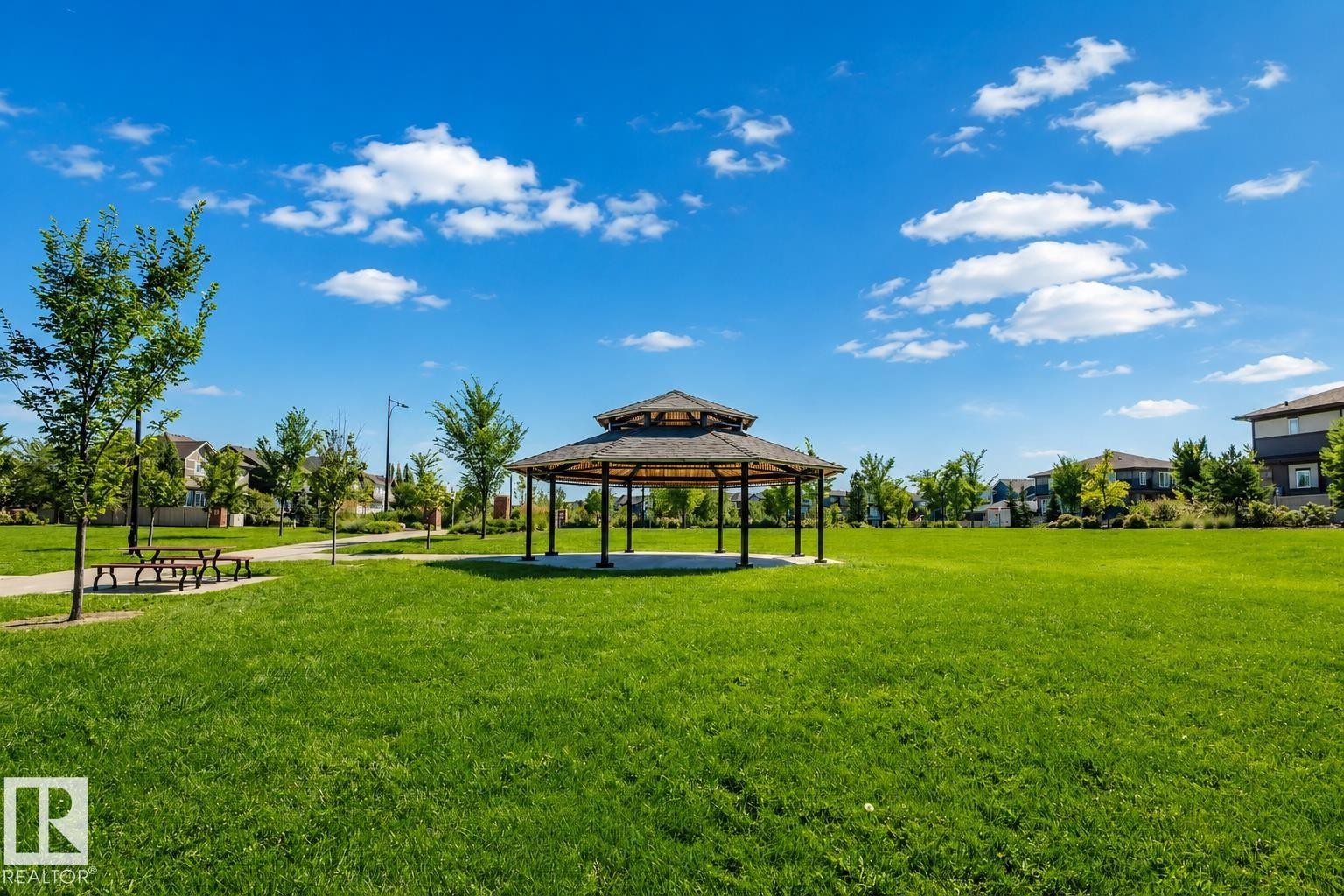 Expansive green space featuring a central gazebo with a multi-tiered roof, surrounded by manicured lawns and mature trees - 4125 Kennedy Green Sw, Edmonton, AB - Outdoor