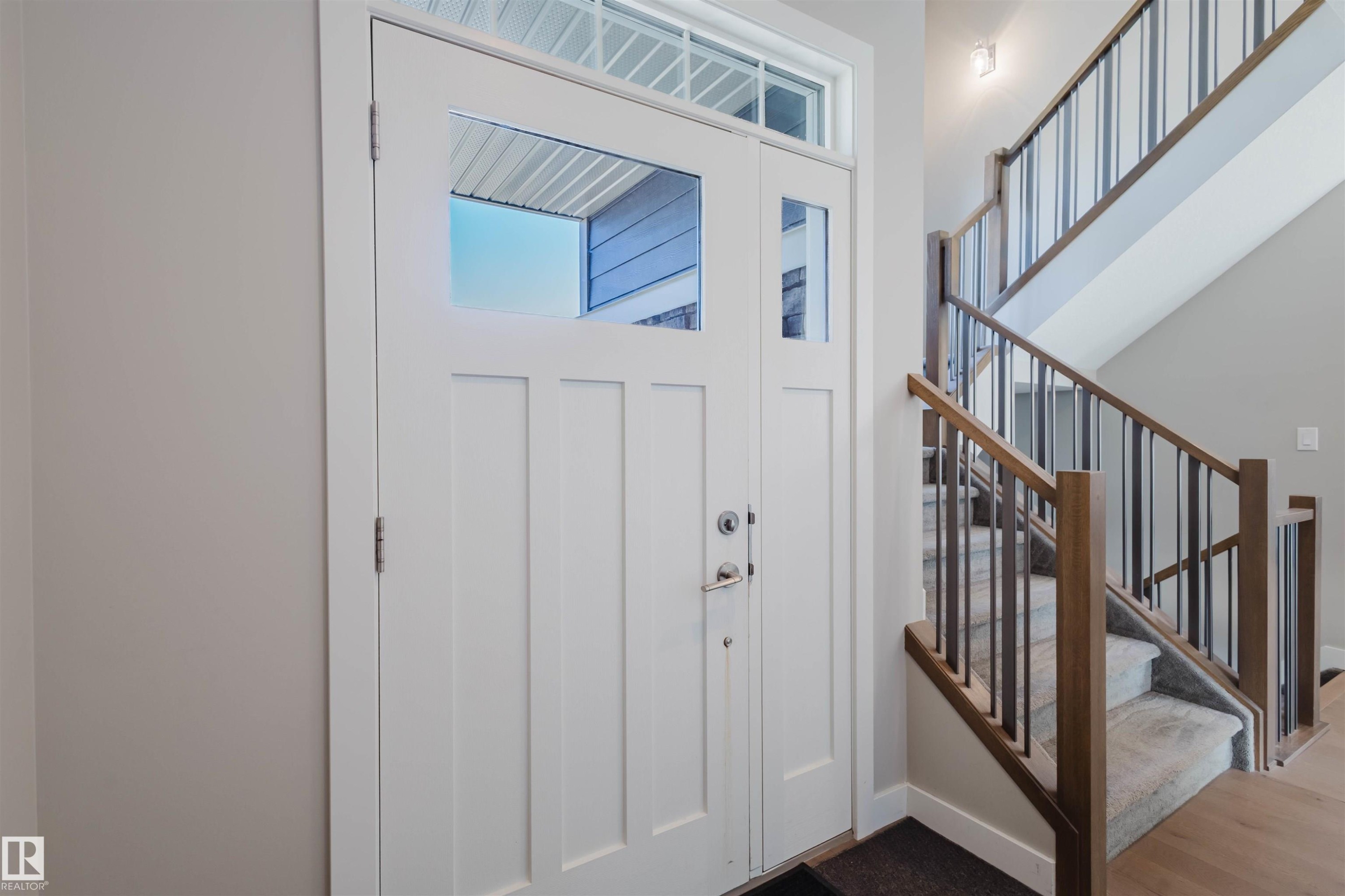 White paneled entry door with clear glass inserts and transom - 4125 Kennedy Green Sw, Edmonton, AB - Indoor Photo Showing Other Room