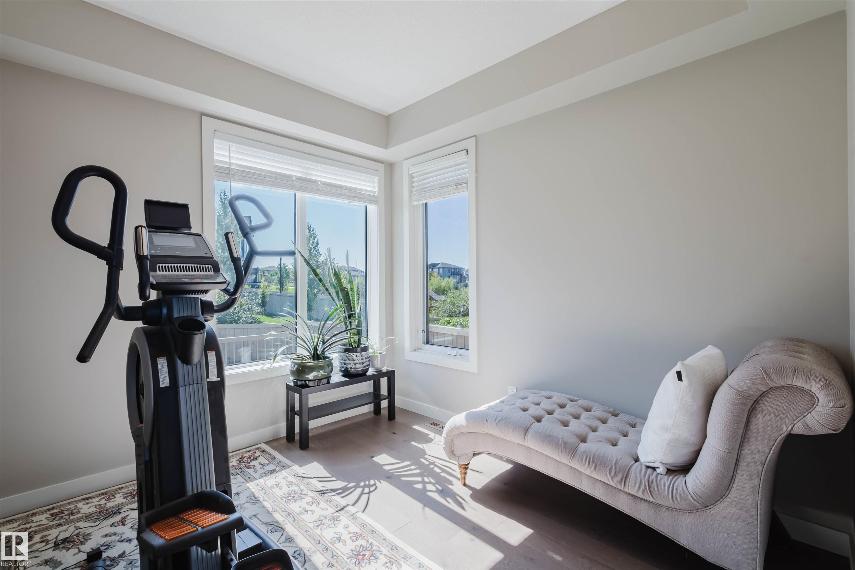 Room featuring light wood-finish flooring, neutral wall tones, and large windows with horizontal blinds - 4125 Kennedy Green Sw, Edmonton, AB - Indoor