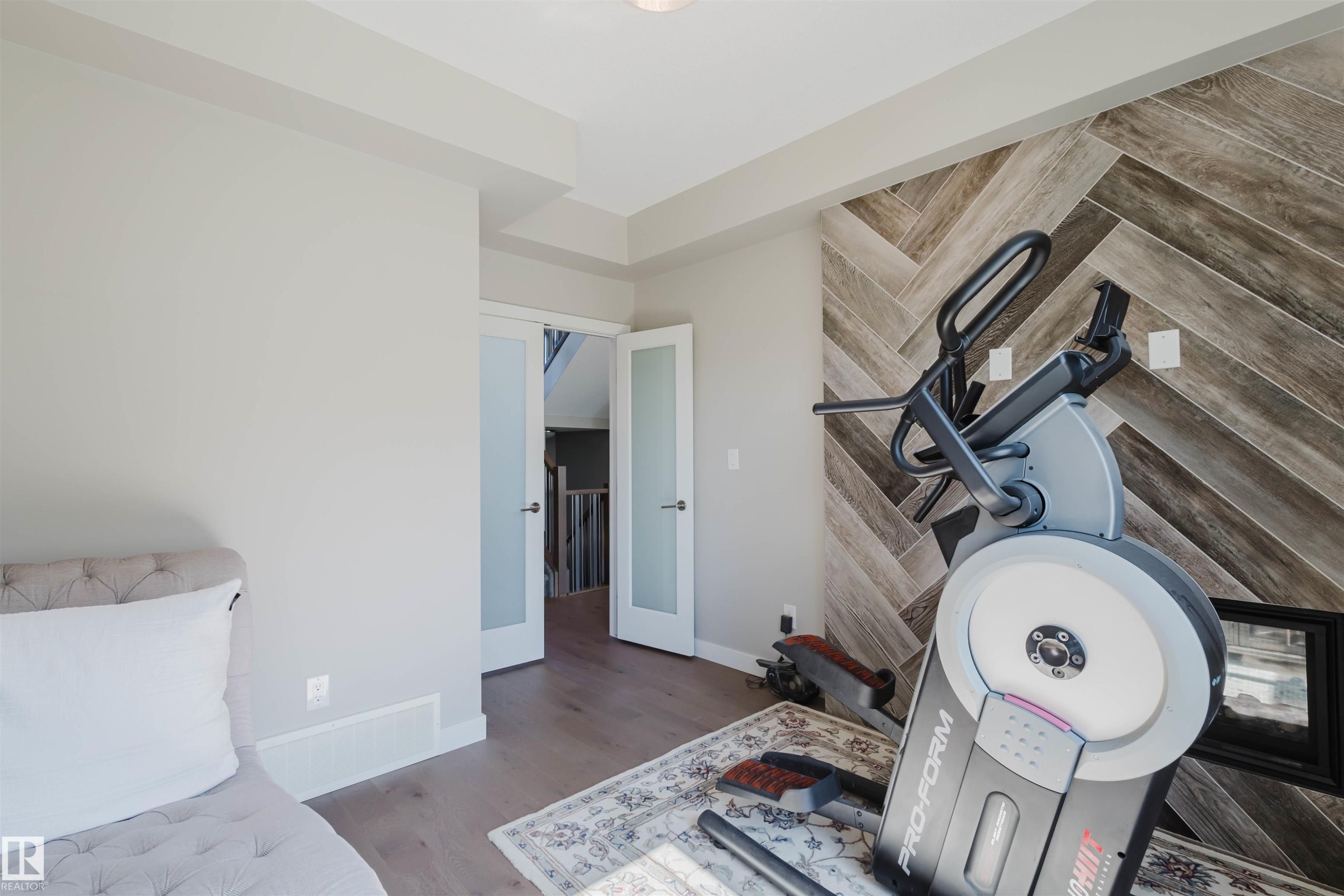 Accent wall featuring a herringbone wood-finish pattern and integrated hearth - 4125 Kennedy Green Sw, Edmonton, AB - Indoor Photo Showing Other Room