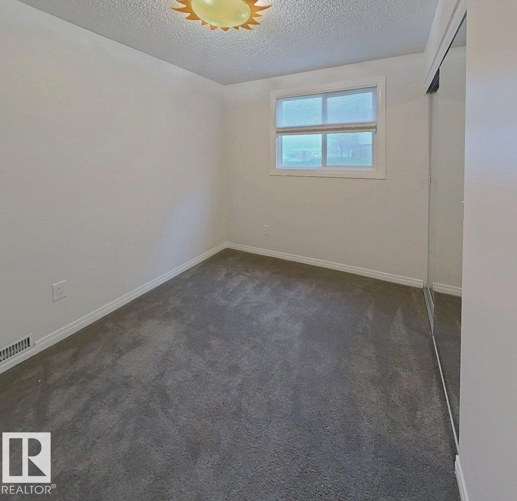 Neutral-toned room featuring a single window, grey carpet flooring, white baseboards, and mirrored closet doors - 60 Northwoods Village Nw, Edmonton, AB - Indoor Photo Showing Other Room