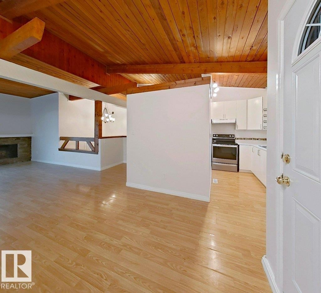 Wood-finish flooring throughout, complemented by a wood-paneled and exposed beam ceiling - 60 Northwoods Village Nw, Edmonton, AB - Indoor With Fireplace