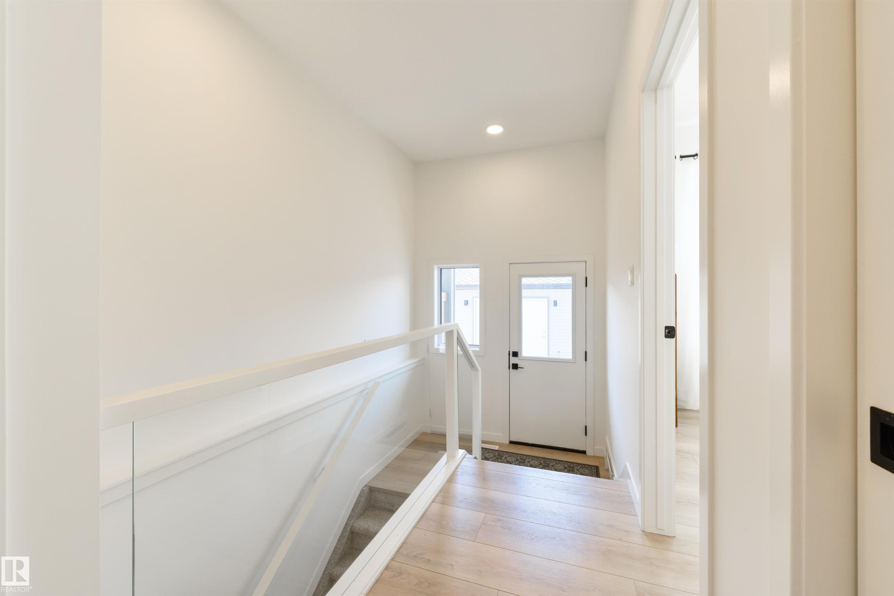 Entryway featuring wood-finish flooring, a white paneled door with a glass insert, and two vertical windows - 323 Rankin Drive, St. Albert, AB - Indoor Photo Showing Other Room