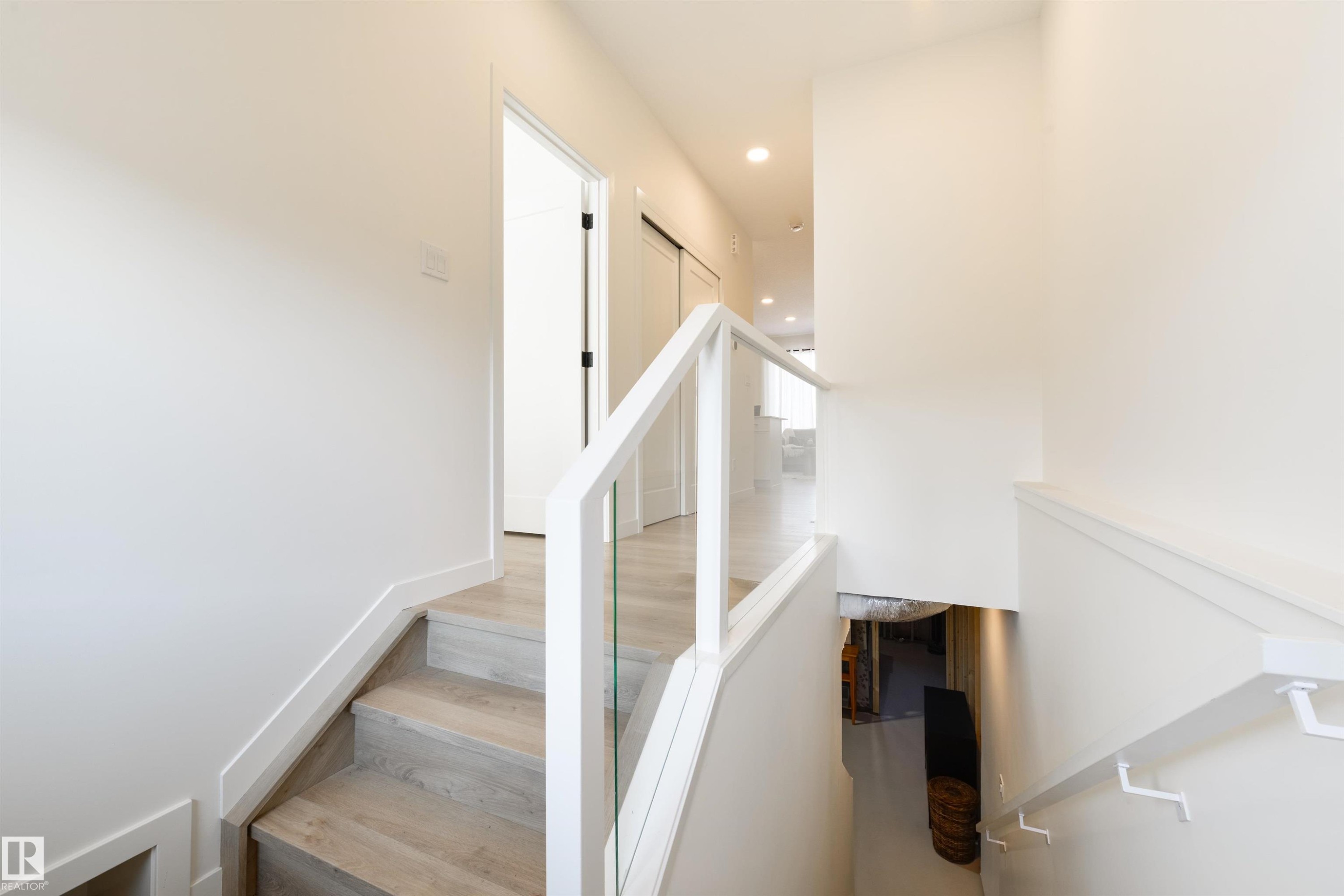 Modern stairway featuring light wood-finish treads and a contemporary glass railing with white balusters - 323 Rankin Drive, St. Albert, AB - Indoor Photo Showing Other Room