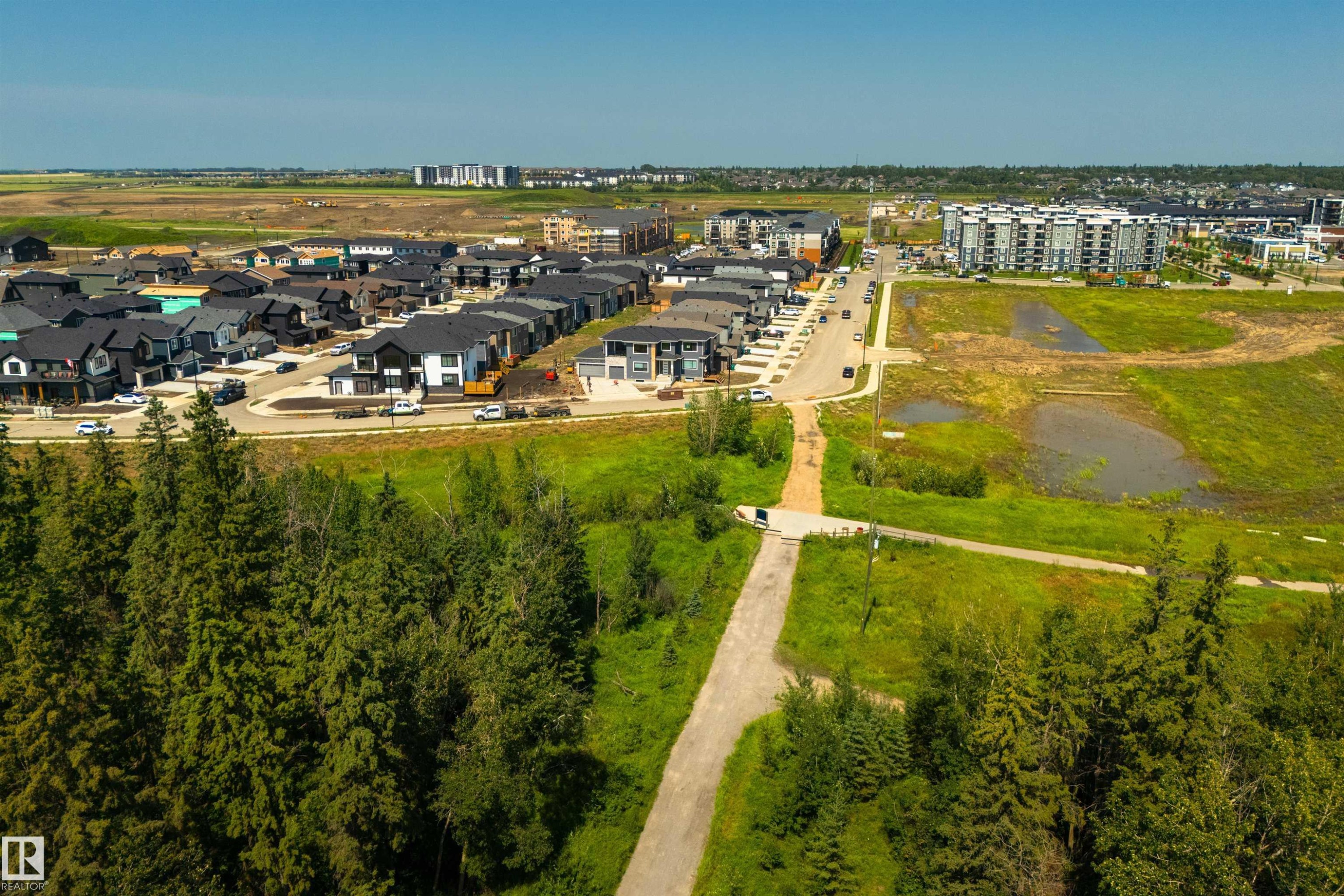 Expansive development area featuring a collection of contemporary homes with dark roofs, mature evergreen trees, and paved roadways - 323 Rankin Drive, St. Albert, AB - Outdoor With View