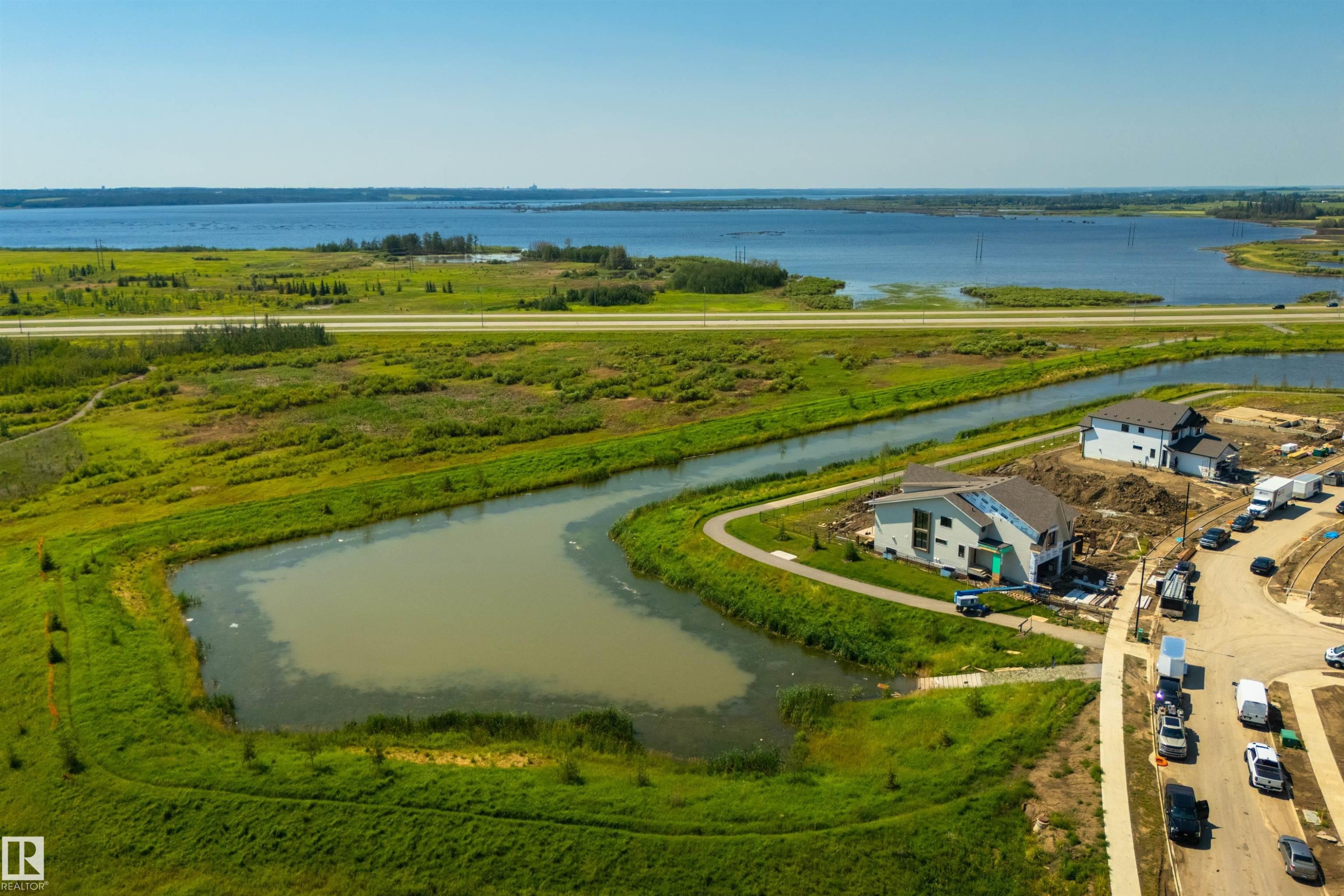 Newly constructed property featuring a modern architectural design, situated alongside a water retention pond and walking path - 323 Rankin Drive, St. Albert, AB - Outdoor With Body Of Water With View