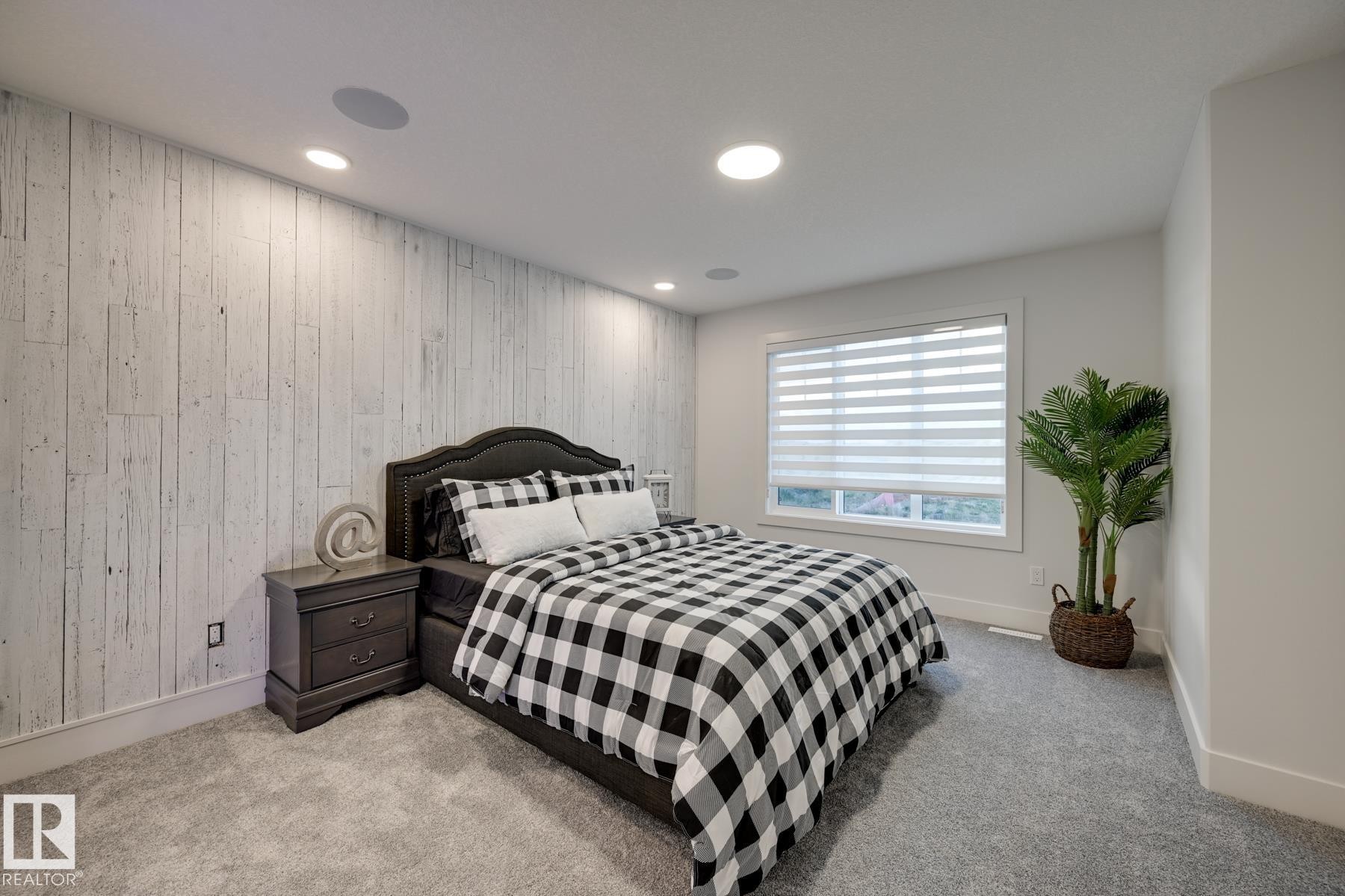 Bedroom featuring a distressed wood-paneled accent wall, recessed lighting, and built-in ceiling speakers - 1776 Crossbill Loop Nw, Edmonton, AB - Indoor Photo Showing Bedroom