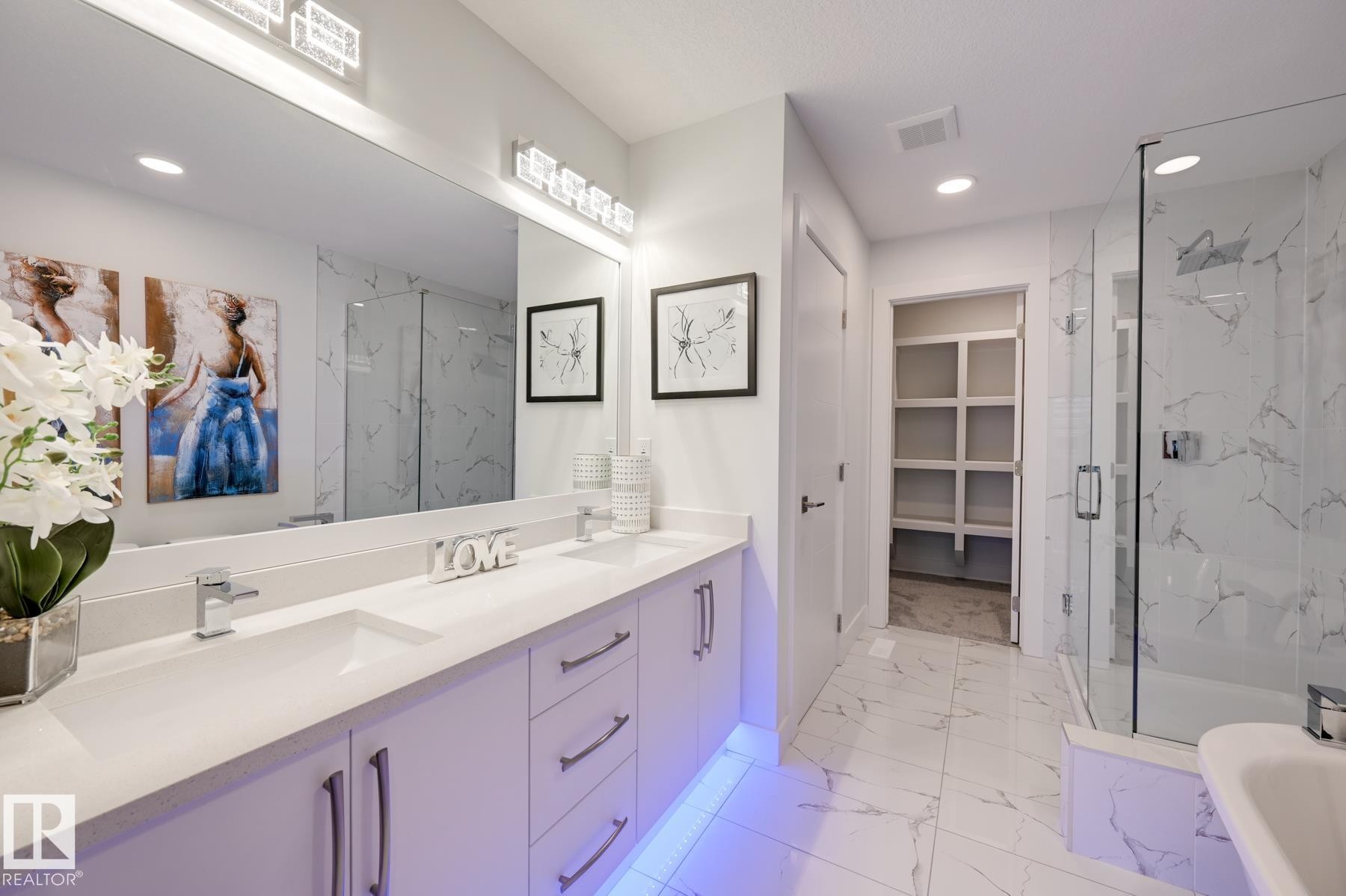 Spacious bathroom featuring a double vanity with ample counter space, built-in cabinetry, and under-cabinet lighting - 1776 Crossbill Loop Nw, Edmonton, AB - Indoor Photo Showing Bathroom