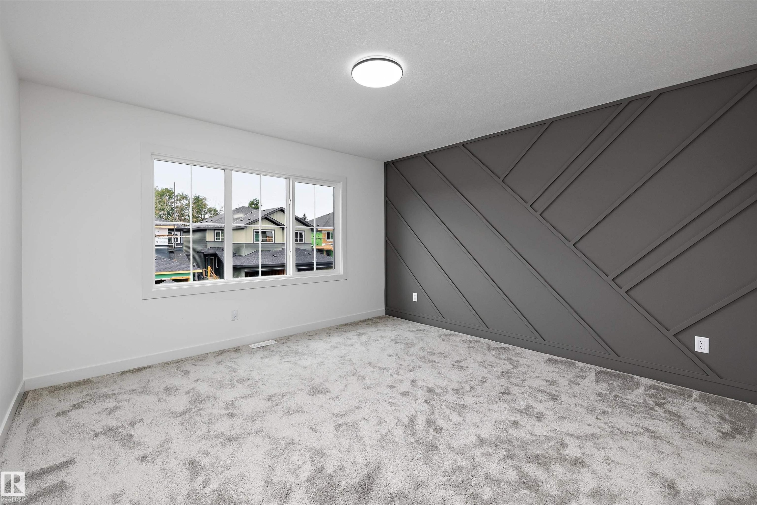Accent wall with geometric paneling, multiple pane window, plush gray carpeting, and flush mount ceiling light - 1776 Crossbill Loop Nw, Edmonton, AB