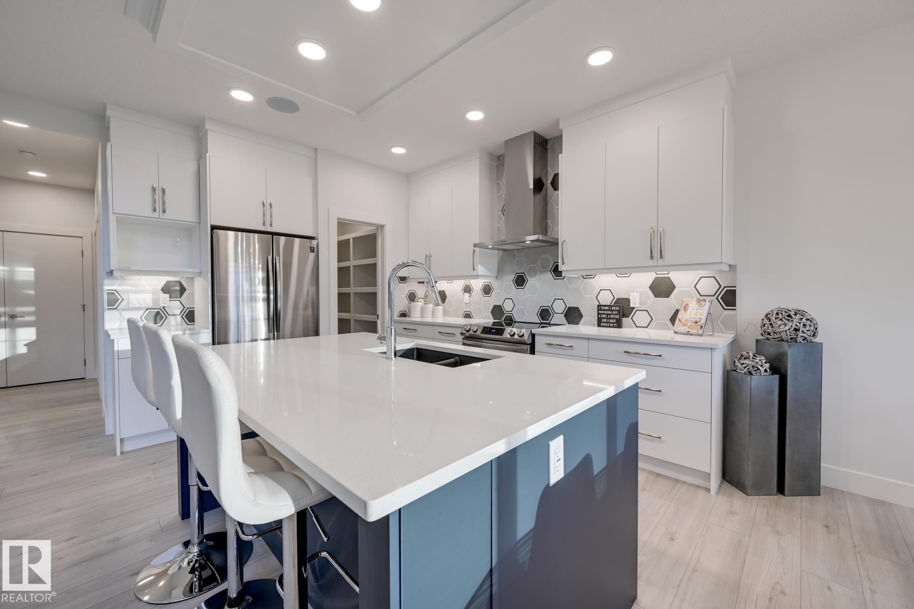 Modern kitchen featuring a large central island with a built-in sink and seating space - 1776 Crossbill Loop Nw, Edmonton, AB - Indoor Photo Showing Kitchen With Double Sink