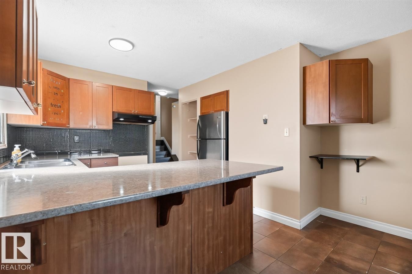 Kitchen featuring wood-finish cabinetry, stainless steel refrigerator, and a built-in oven - 4003 41 Avenue Nw, Edmonton, AB - Indoor Photo Showing Kitchen With Double Sink