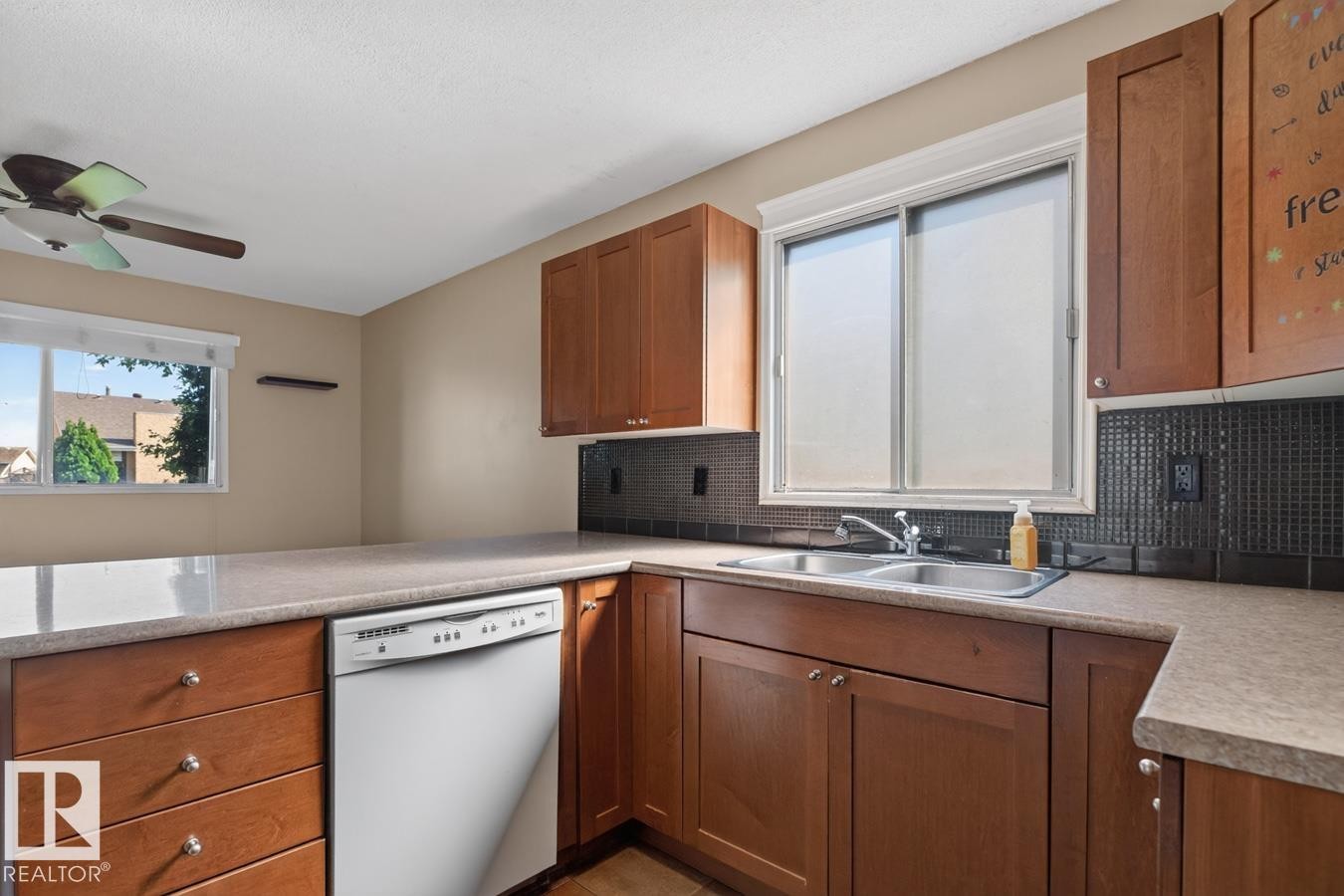 Kitchen featuring wood cabinetry, stone-finish countertops, and a black tile backsplash - 4003 41 Avenue Nw, Edmonton, AB - Indoor Photo Showing Kitchen With Double Sink