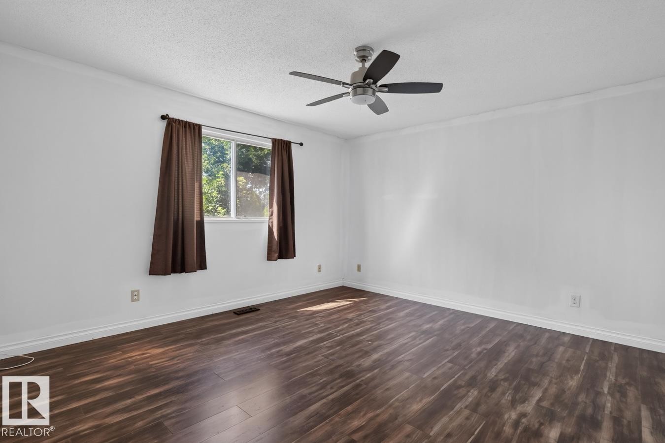 Spacious room featuring wood-finish flooring, white walls, and crown molding - 4003 41 Avenue Nw, Edmonton, AB - Indoor Photo Showing Other Room