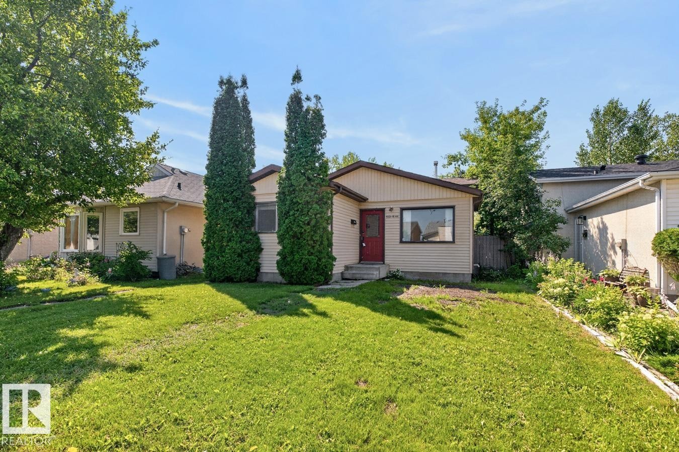 Single-story residence featuring light-colored siding, a dark red entry door, and a partially sloped roofline - 4003 41 Avenue Nw, Edmonton, AB - Outdoor