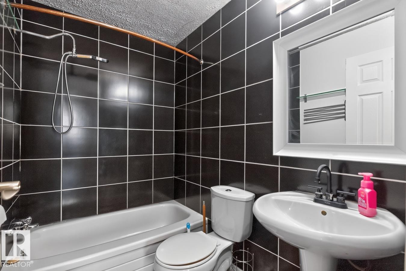 Bathroom featuring subway tile surround, pedestal sink with matte black faucet, and white framed mirror - 4003 41 Avenue Nw, Edmonton, AB - Indoor Photo Showing Bathroom