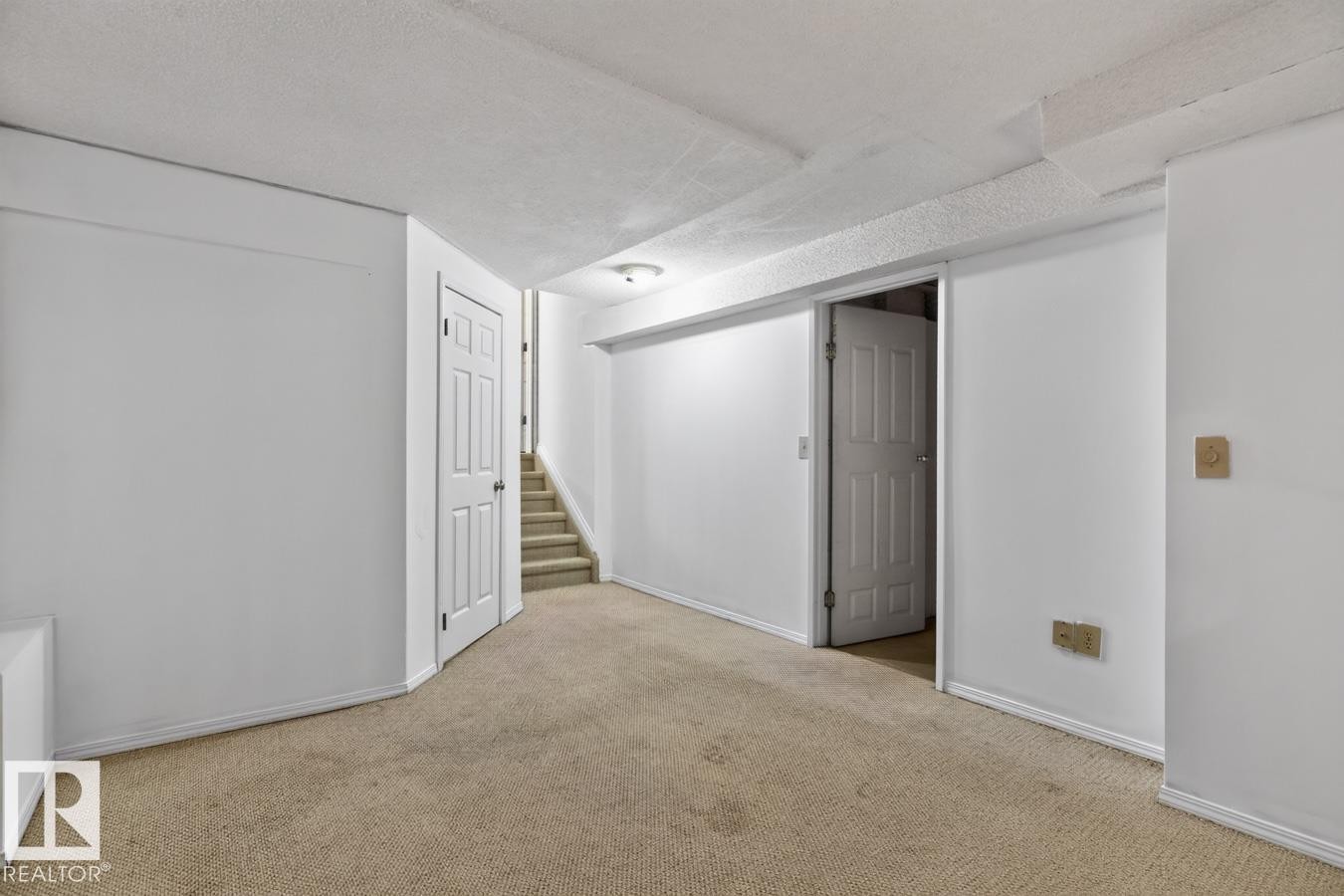 Finished lower level featuring neutral carpeting, white trim, and a white six-panel door - 4003 41 Avenue Nw, Edmonton, AB - Indoor Photo Showing Other Room