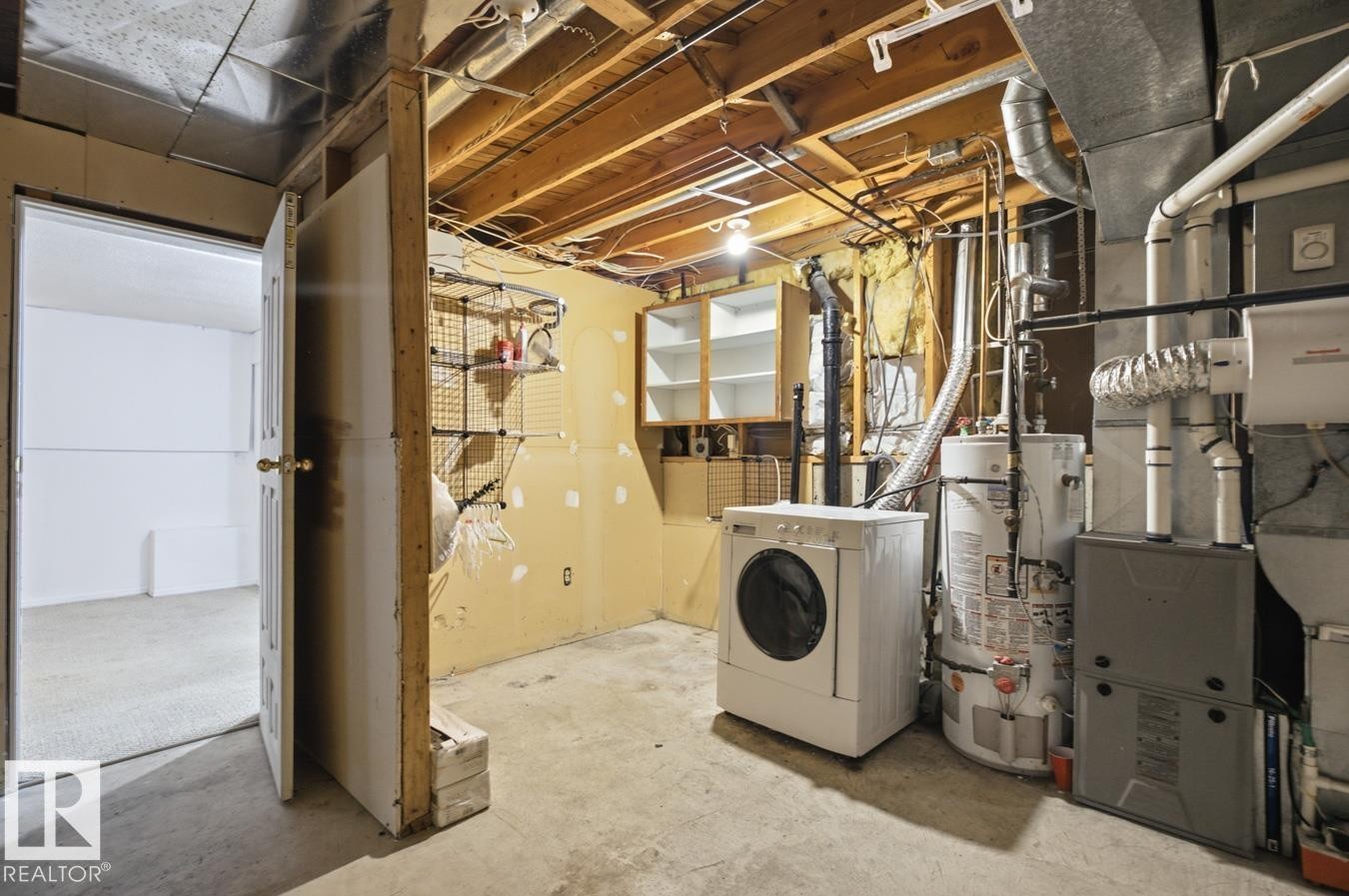 Unfinished basement space featuring exposed ceiling joists, concrete flooring, and a utility area with a water heater and furnace - 4003 41 Avenue Nw, Edmonton, AB - Indoor Photo Showing Laundry Room